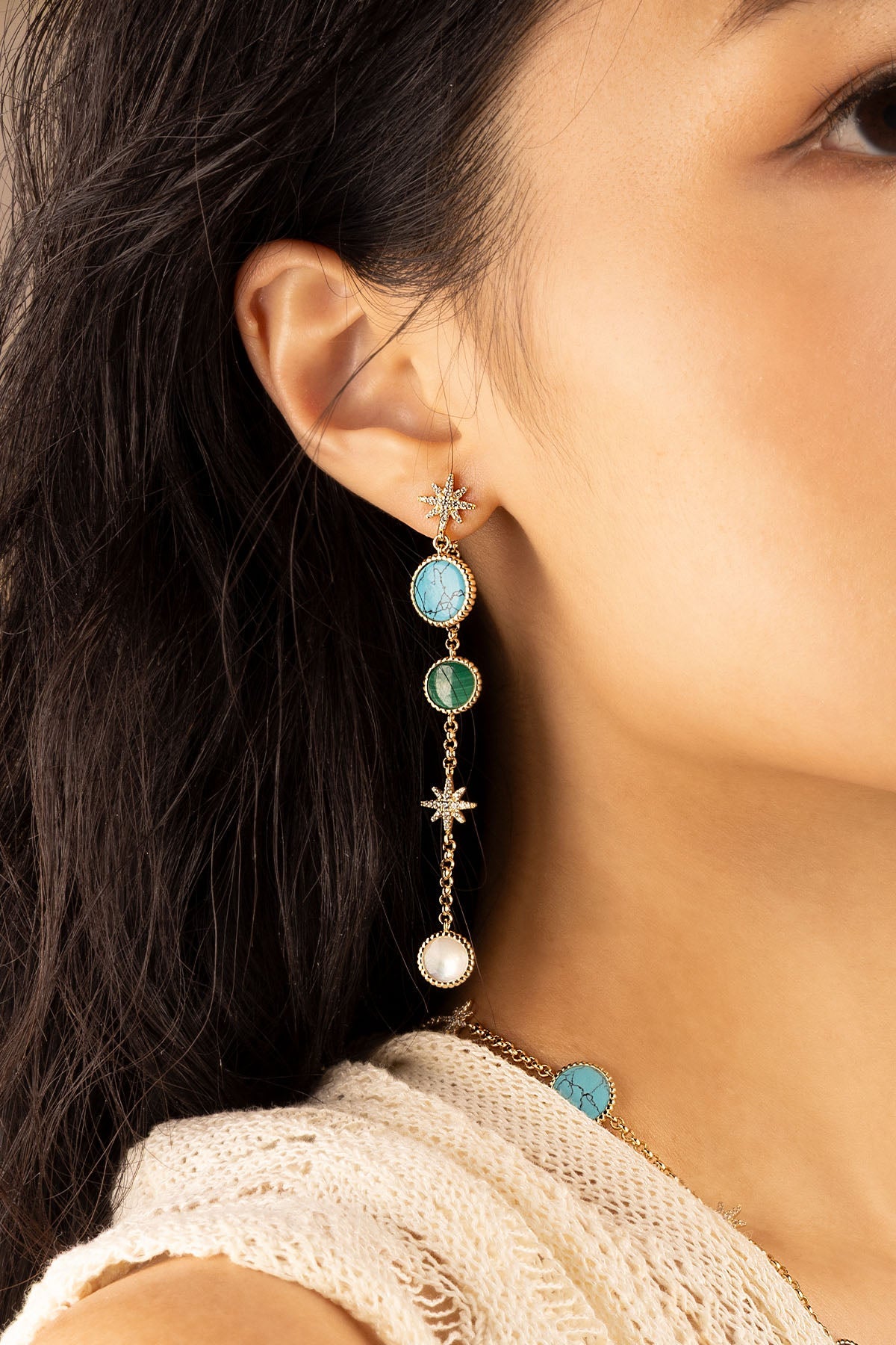 Earrings APM Monaco. Long yellow-gold ear jackets with three round white stones and two star accents.