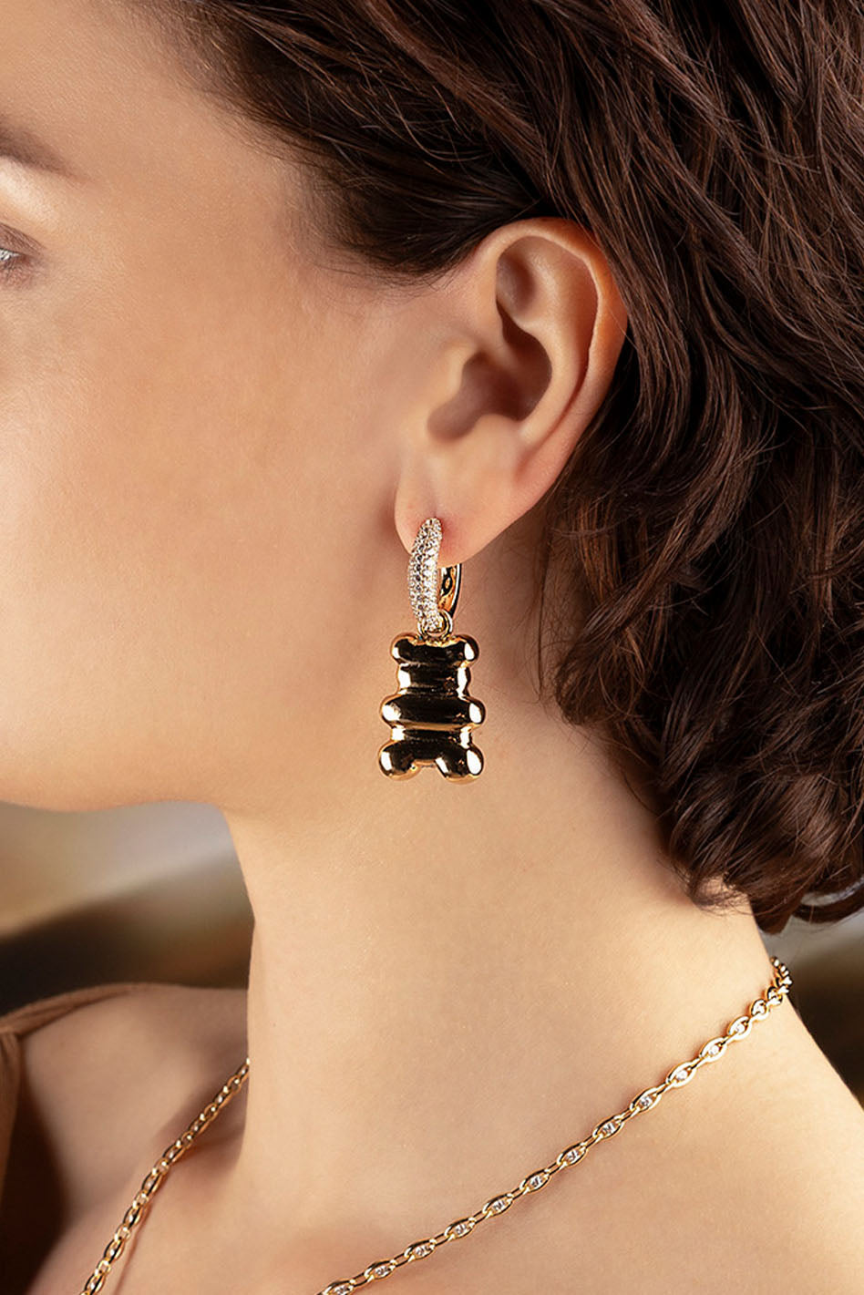 Earrings, APM Monaco: yellow-gold hoop with bear-shaped charm; Loulou Yummy collection; glossy finish and playful accent.