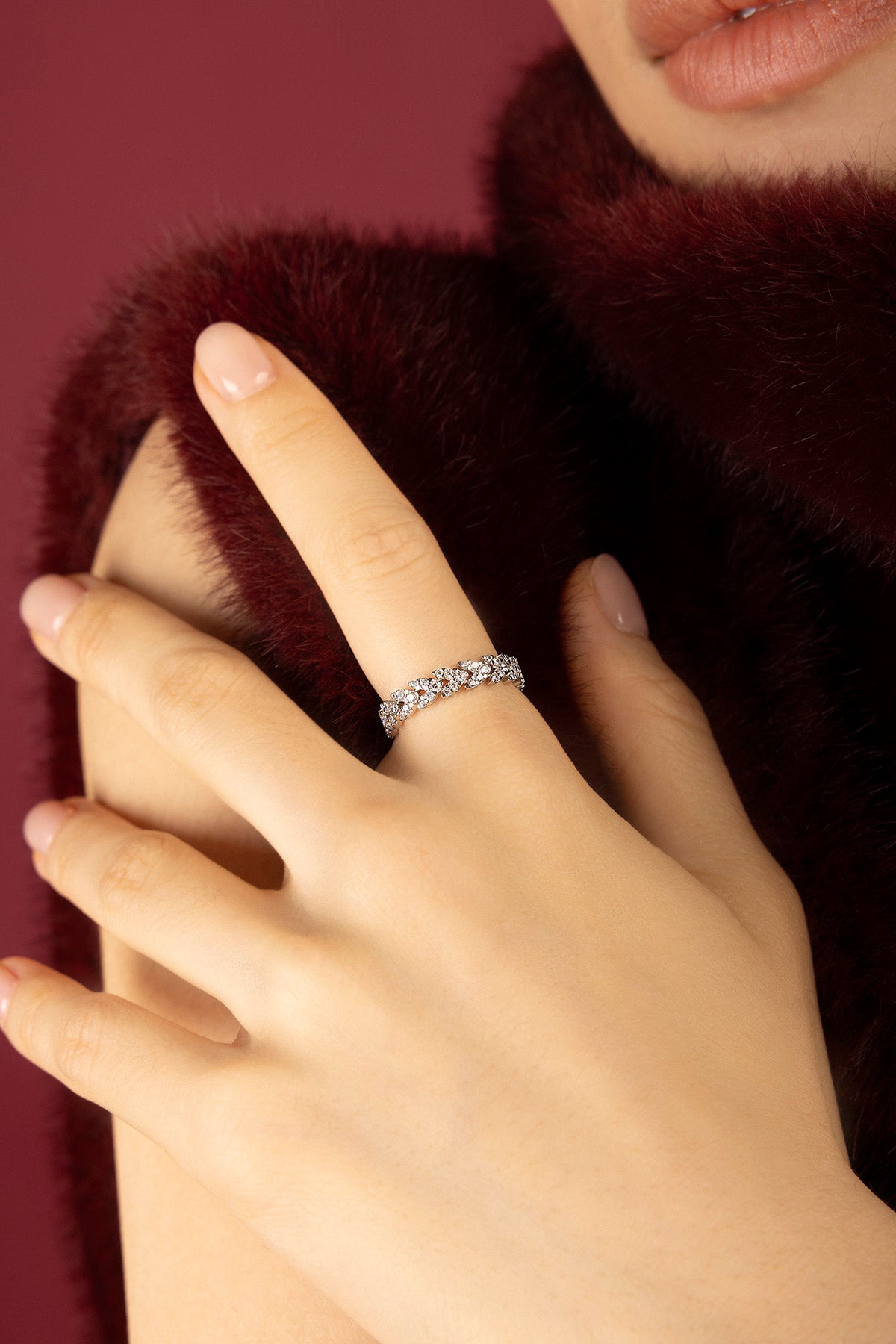 Woman wearing APM Monaco ring, a shimmering whisper against velvet warmth.