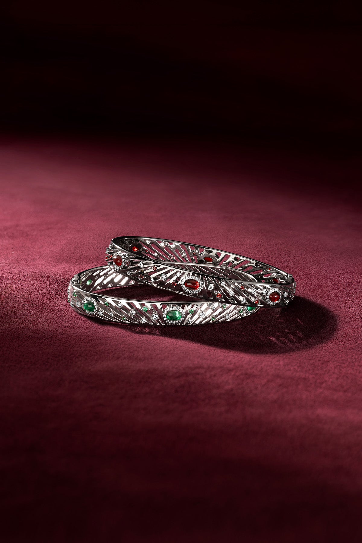 APM Bangles in rhodium finish, glowing with red and green whispers of allure.