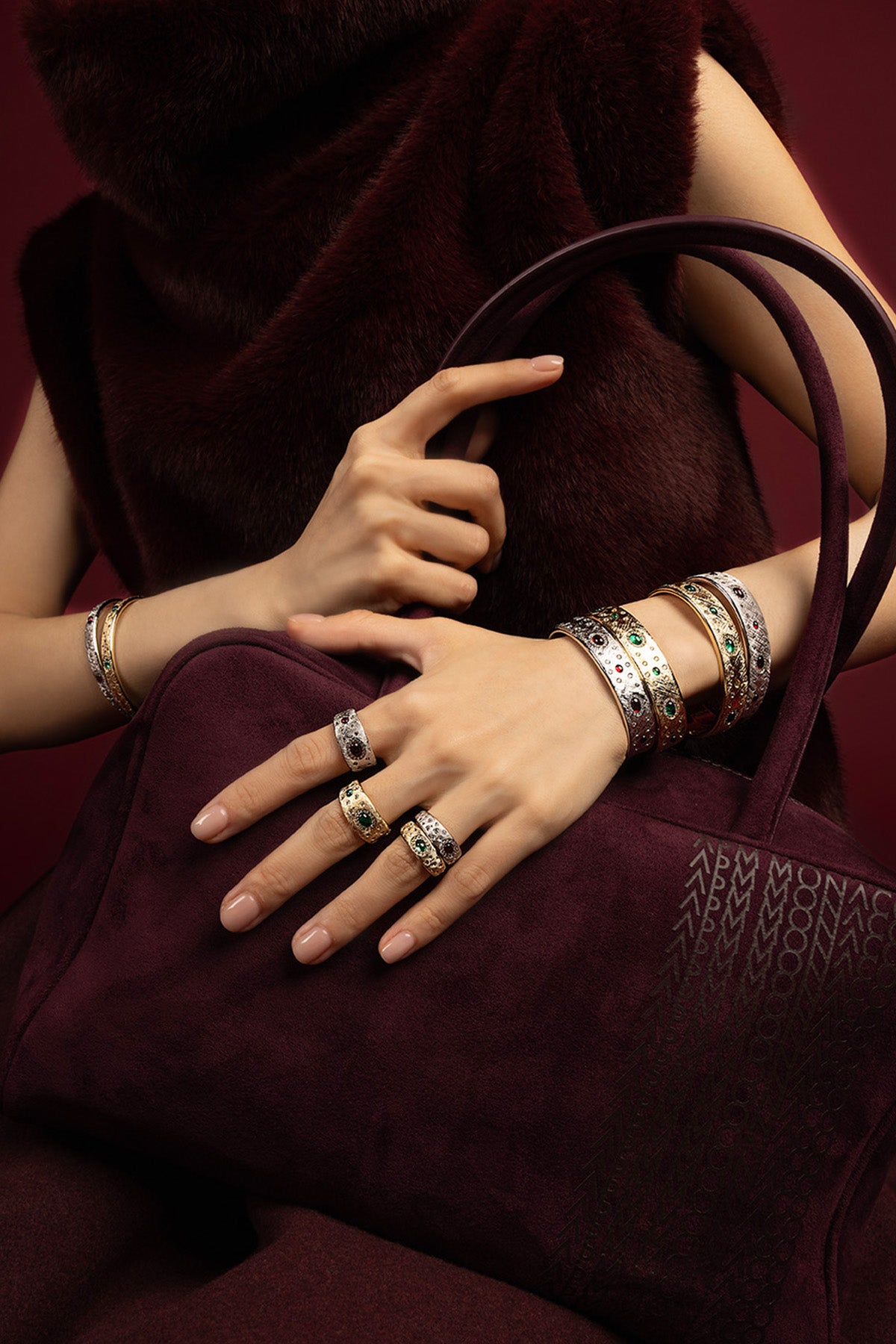 Woman wearing APM Monaco bangles and rings, a jeweled statement in rich burgundy elegance.