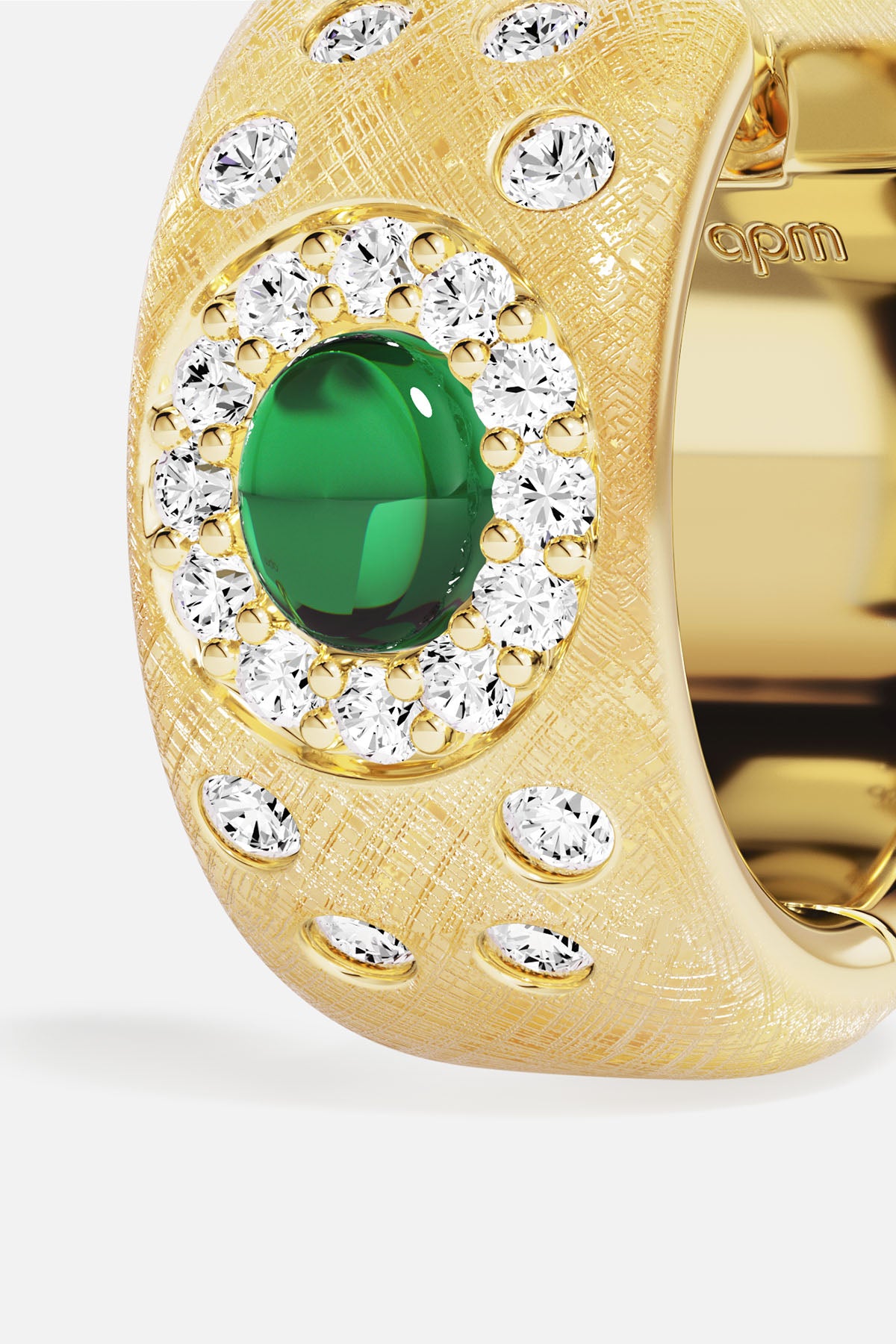 APM Ring in golden hues, a green gem glowing at its heart.