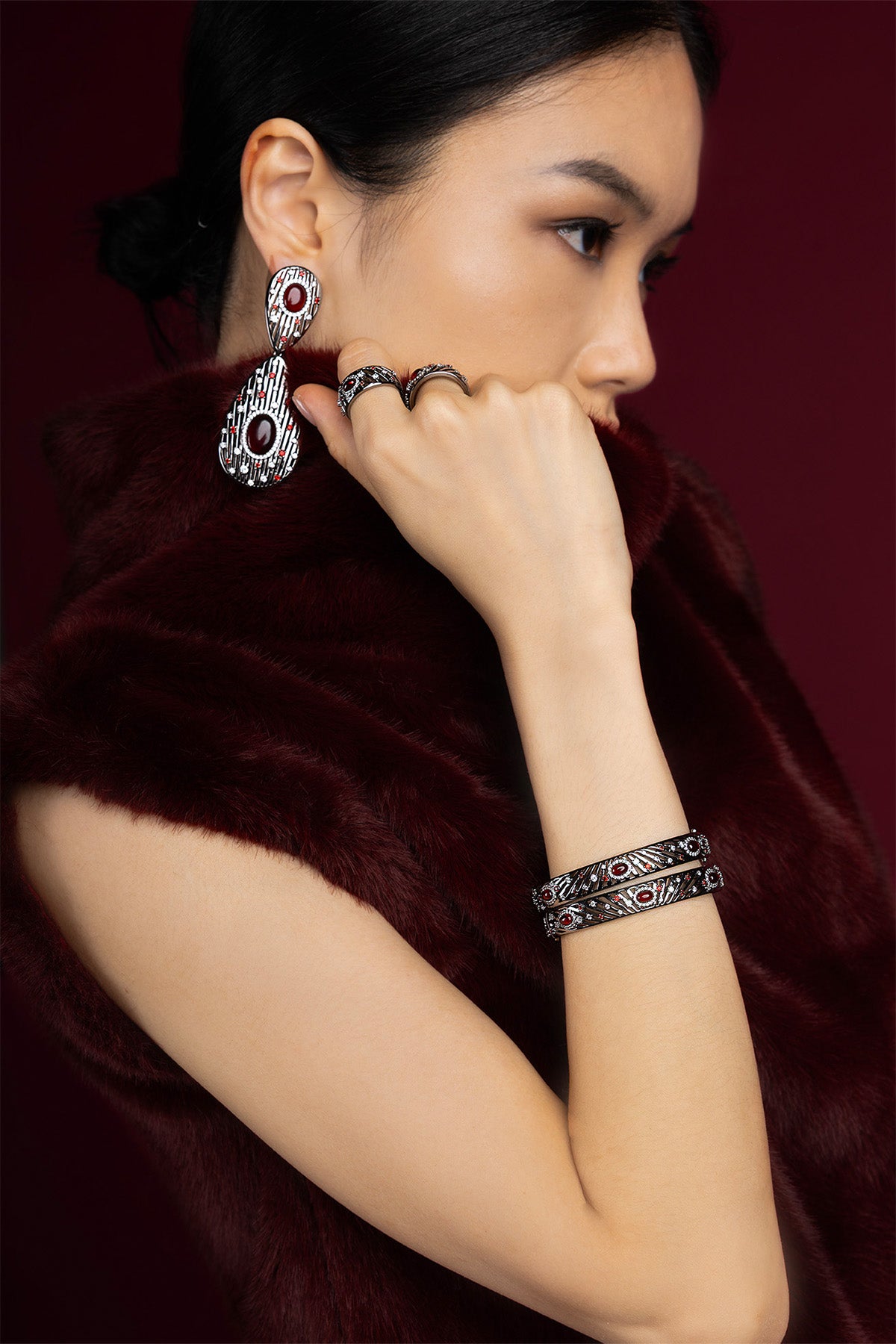 Woman wearing APM Monaco jewelry set, deep red allure wrapped in quiet sophistication.
