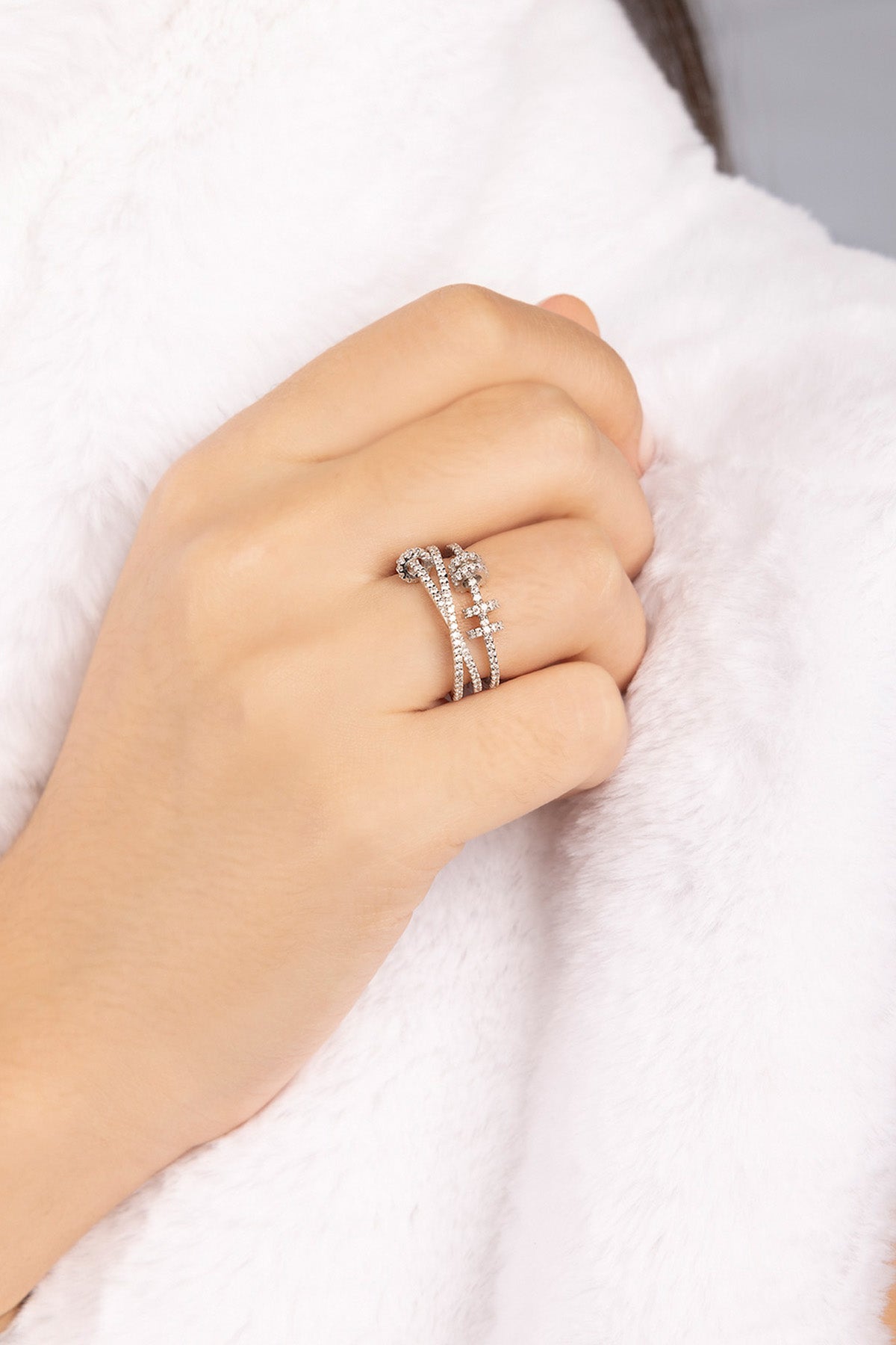 Hand wearing APM MONACO silver ring with sliding hoops design on a white background