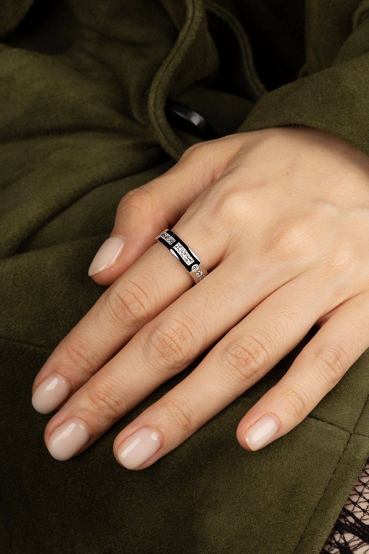 Close-up of a hand wearing a ring on a green fabric background