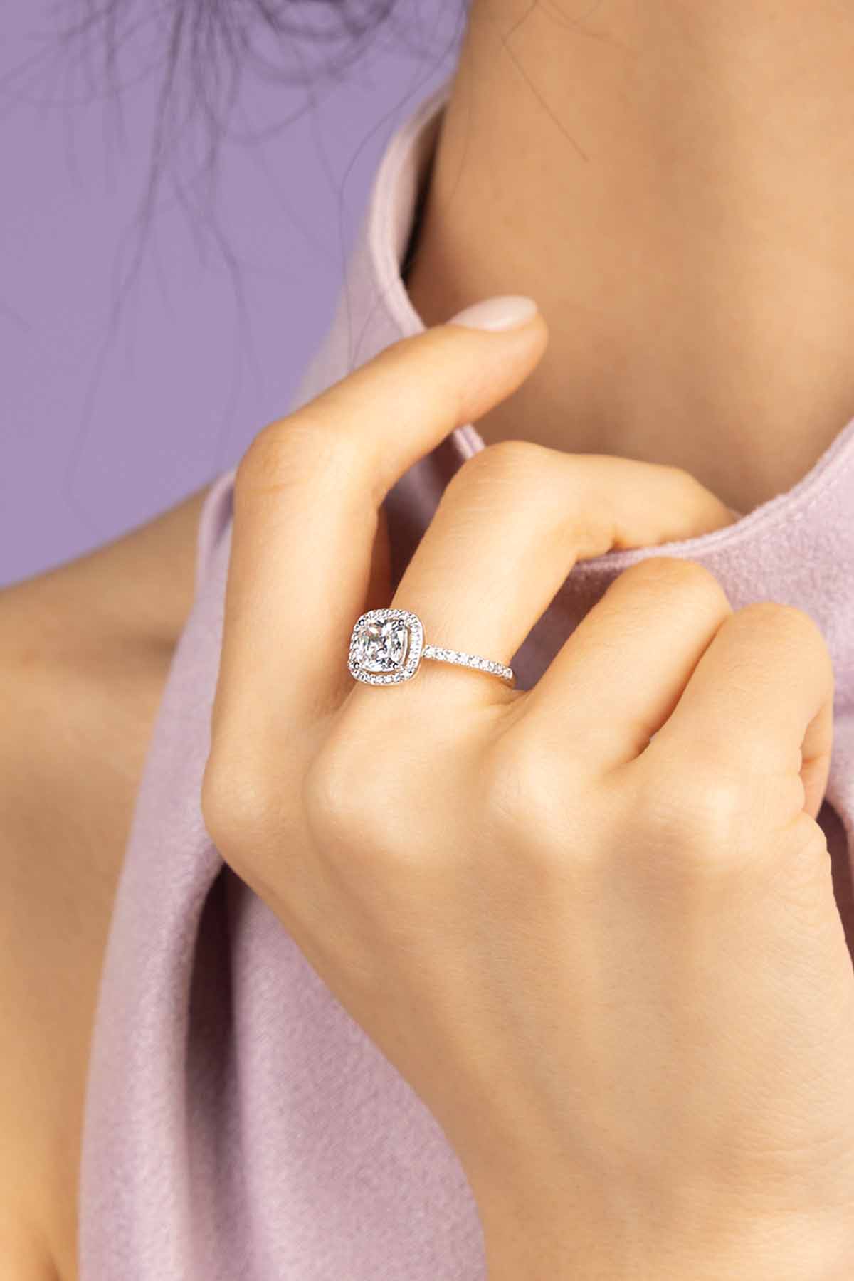 Close-up of a hand wearing APM MONACO small square ring with a blurred purple background