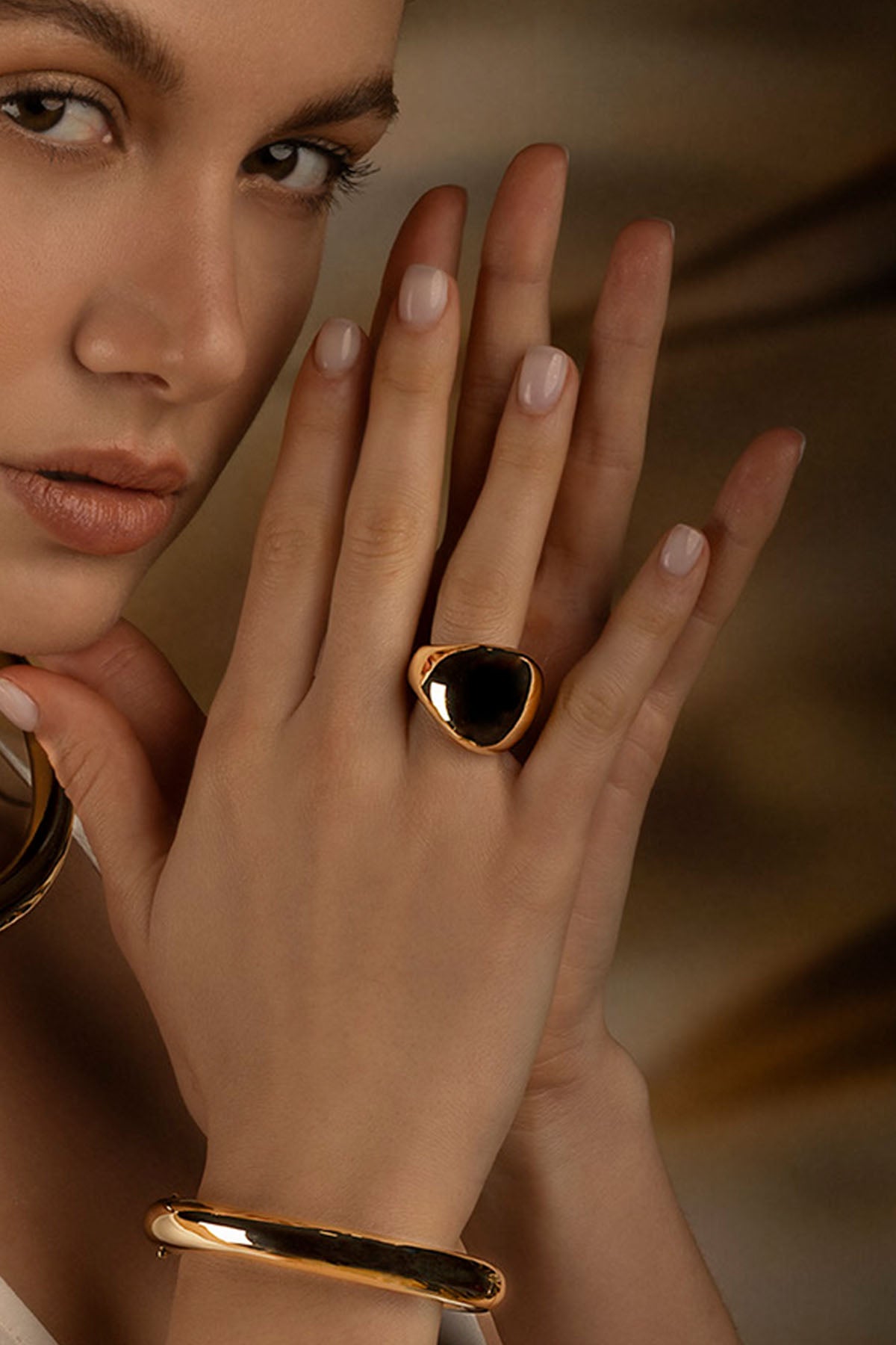 Rings APM Monaco, yellow gold ring with a black stone on the middle finger, bold statement style.