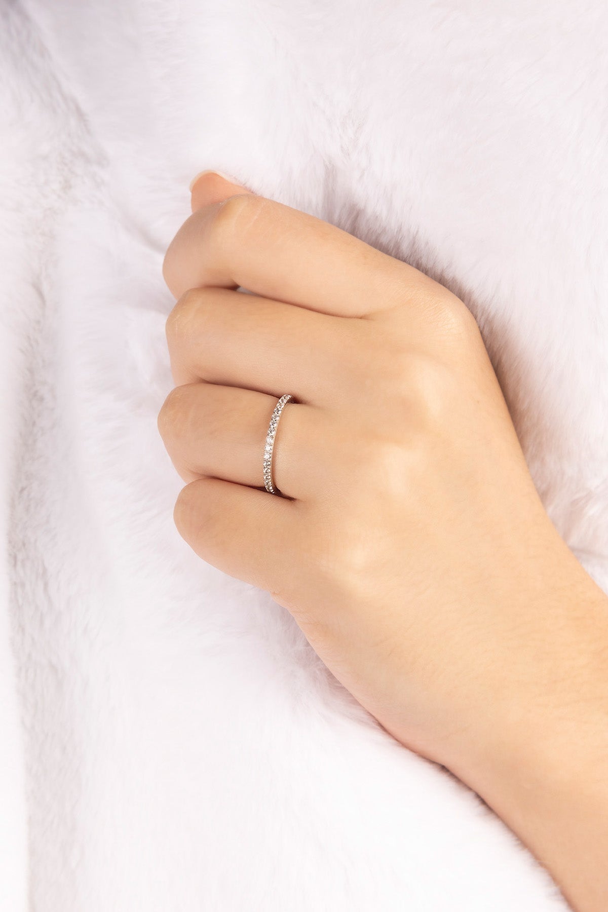 Hand wearing APM MONACO silver ring with linear pave design on a white background