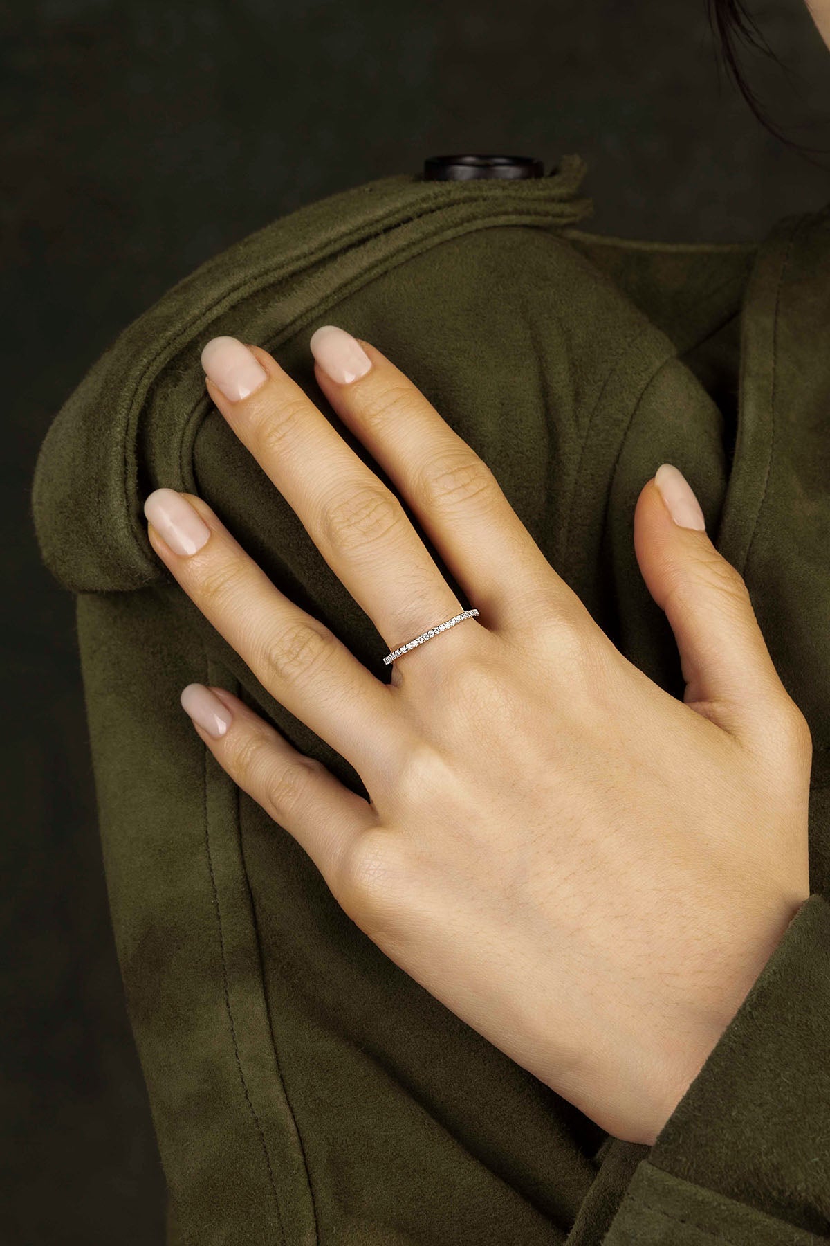 Hand wearing a silver ring on a dark background