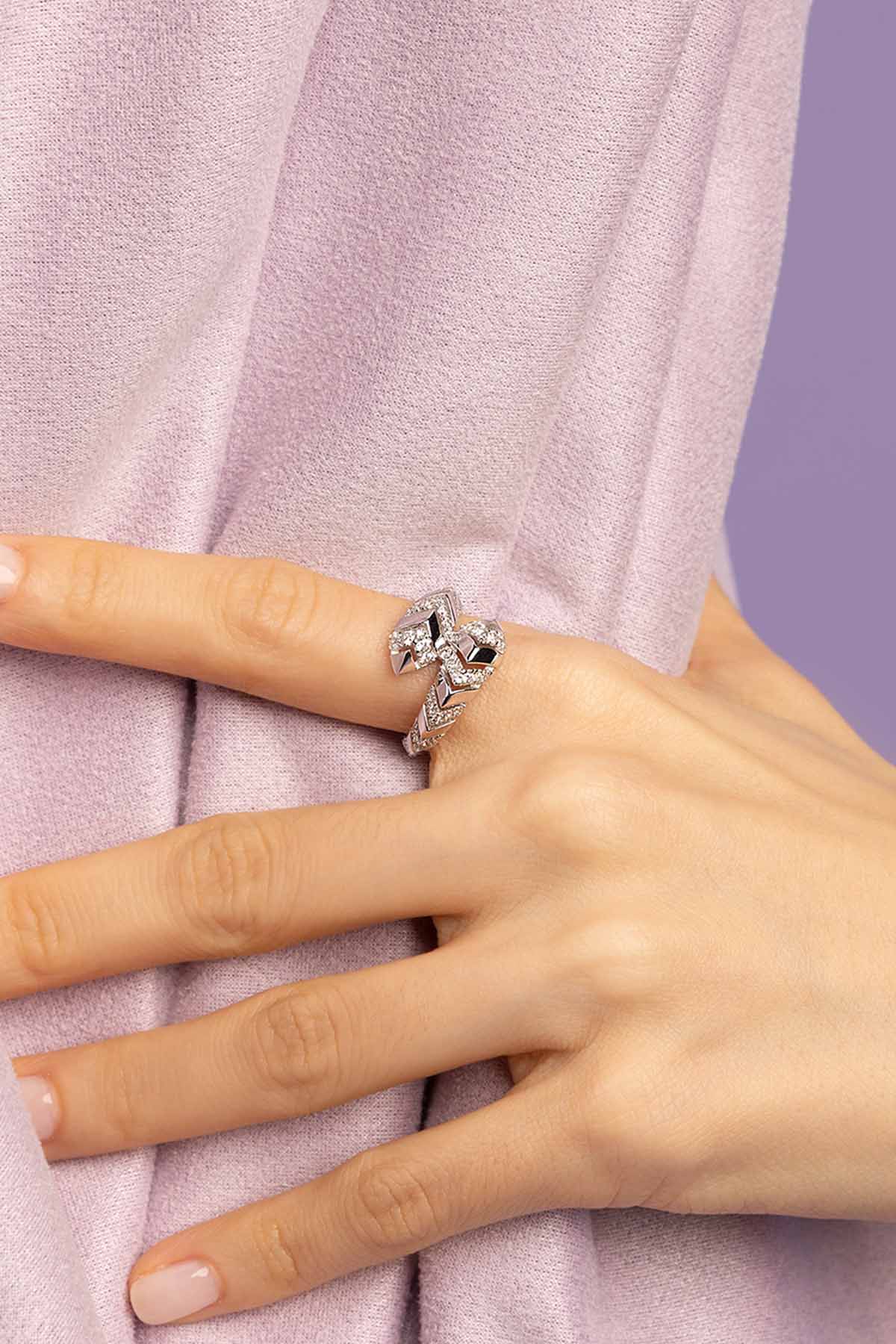 Close-up of a hand wearing a silver ring with a zirconia on a light purple fabric background