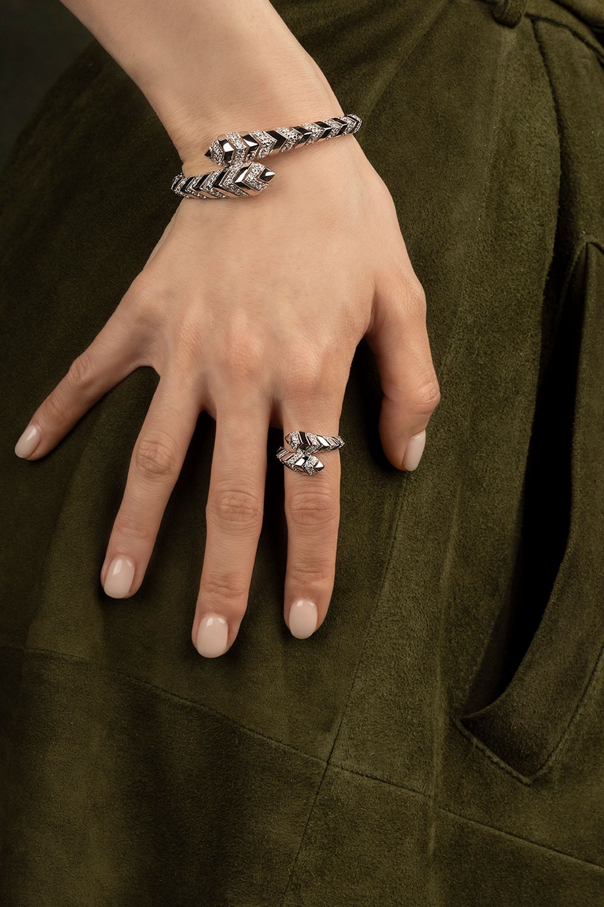 Hand wearing a silver bracelet and ring on a dark background
