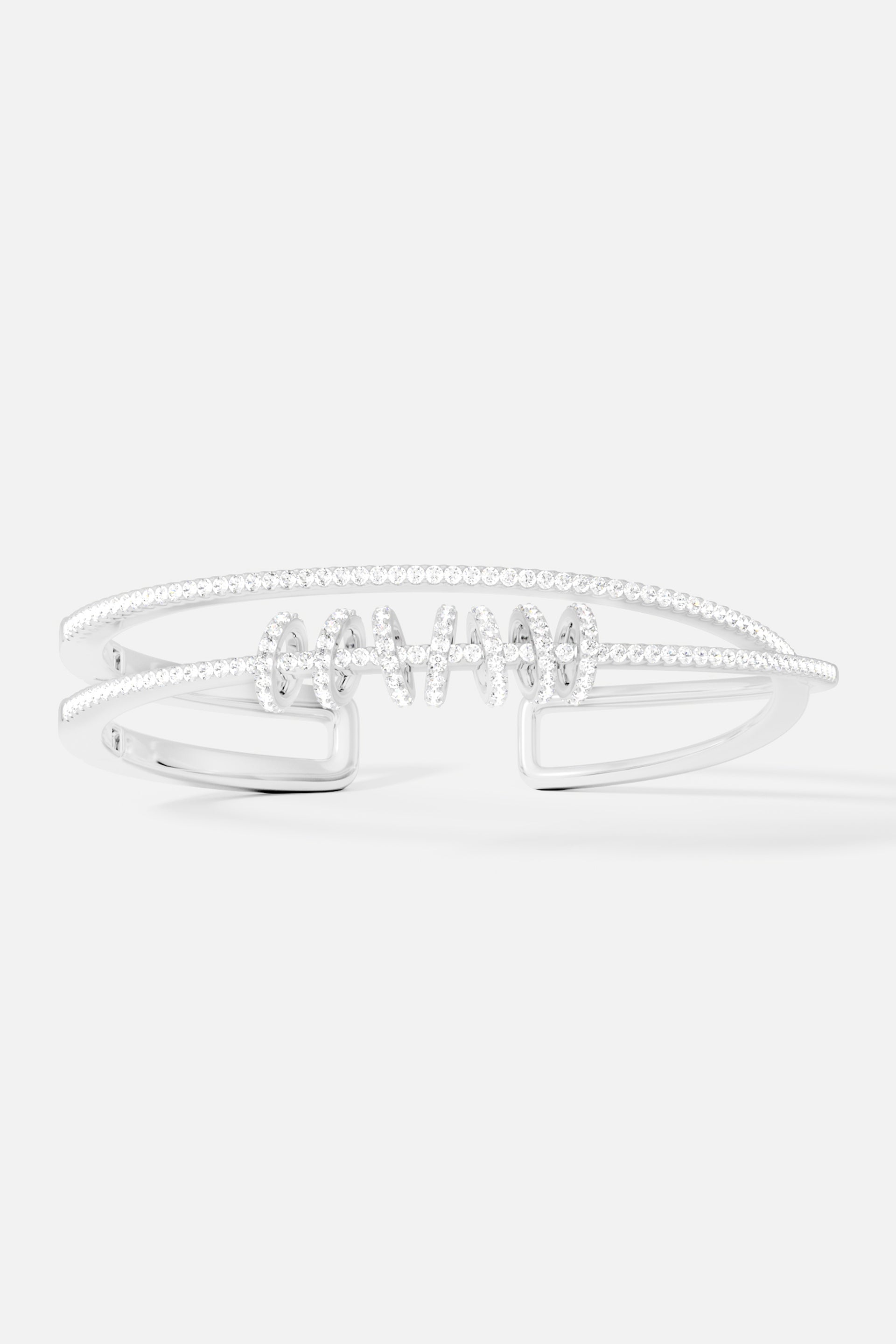 Bracelets APM Monaco. Silver-tone double-open cuff with sliding rings and a row of pavé clear stones along the edge.