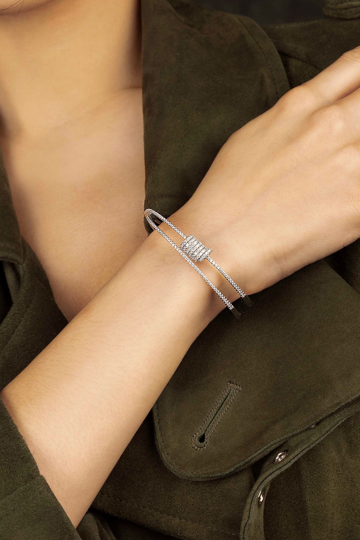Silver bracelet on a person's wrist with a dark green jacket