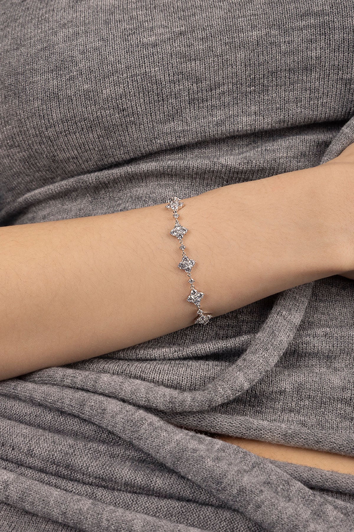 Bracelets APM Monaco, silver-tone pavé bracelet with diamond-like stones on a woman's wrist.