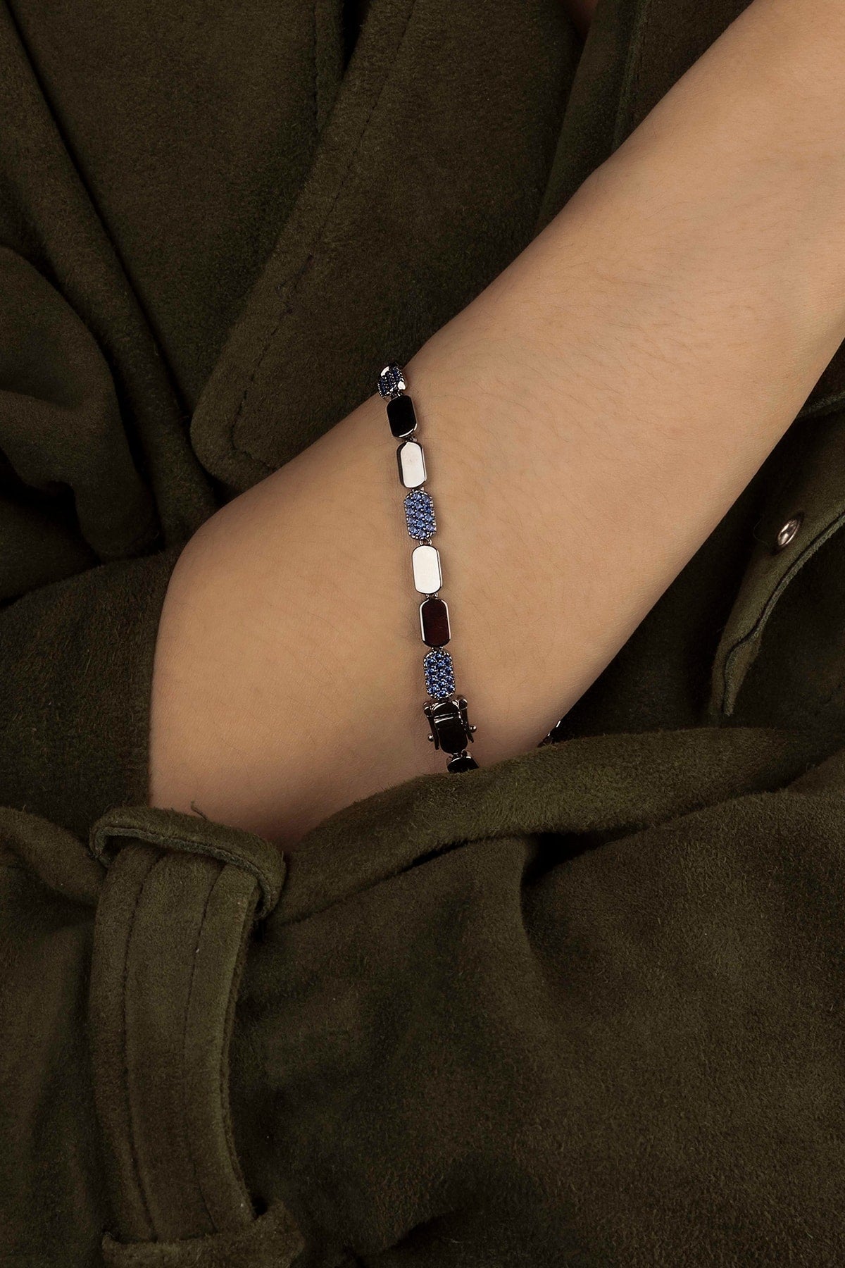 Bracelet with blue stones on a wrist against a dark background