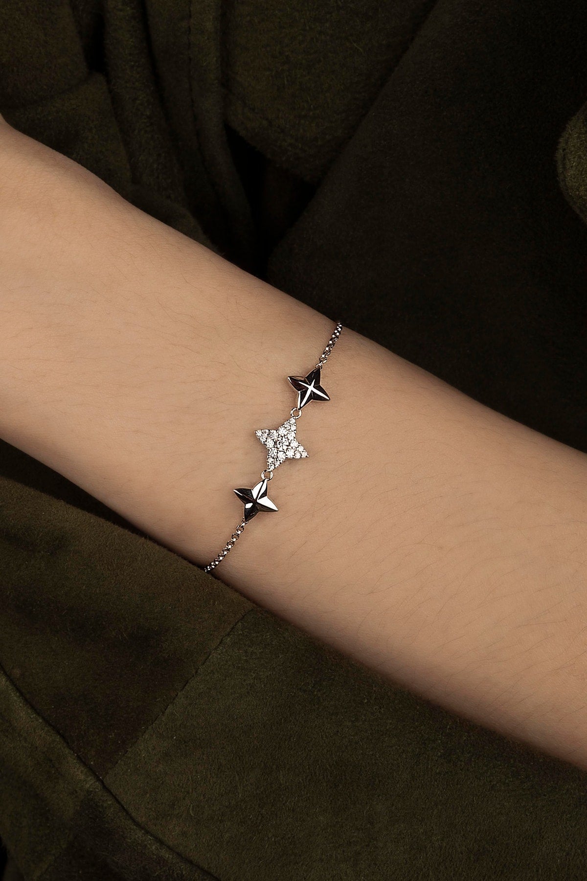 Star-shaped bracelet on a wrist with a green dark background