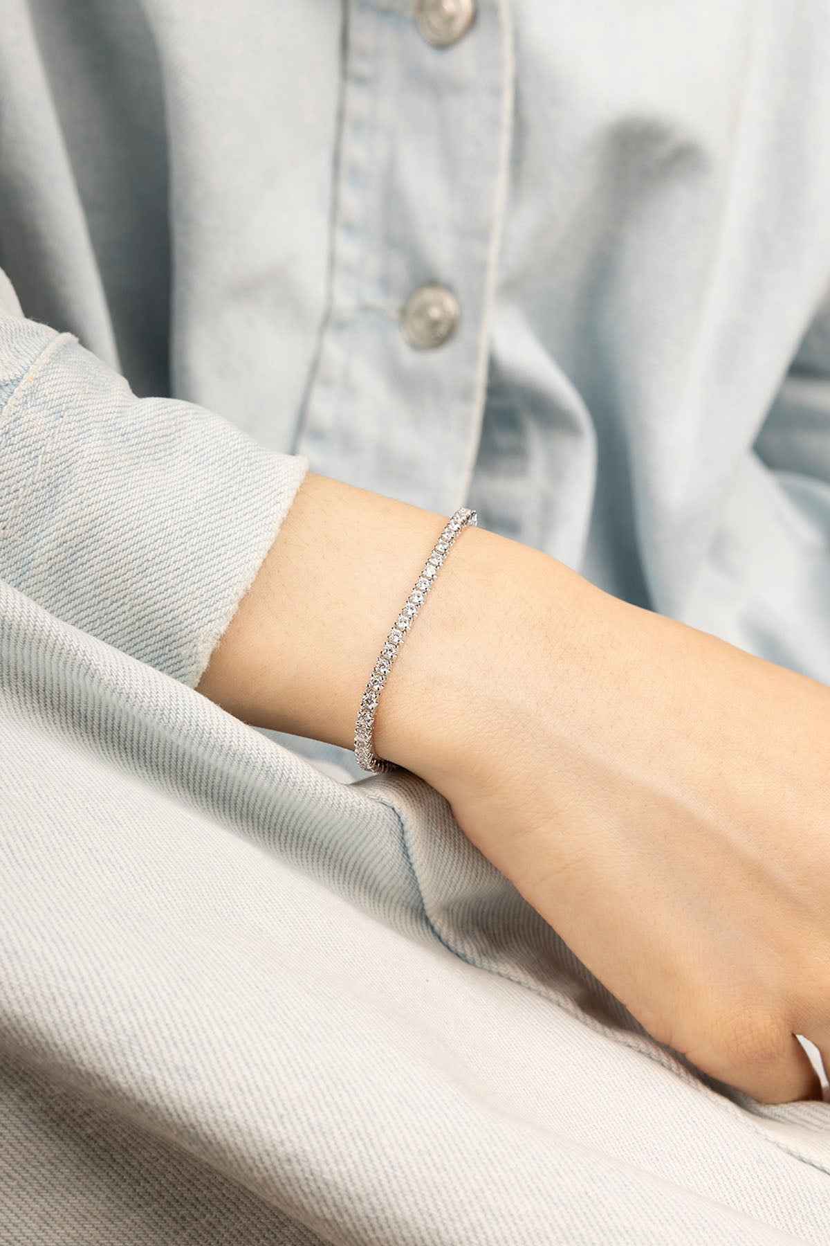 Bracelets APM Monaco tennis bracelet with pavé white stones set in silver-tone metal on the wrist.