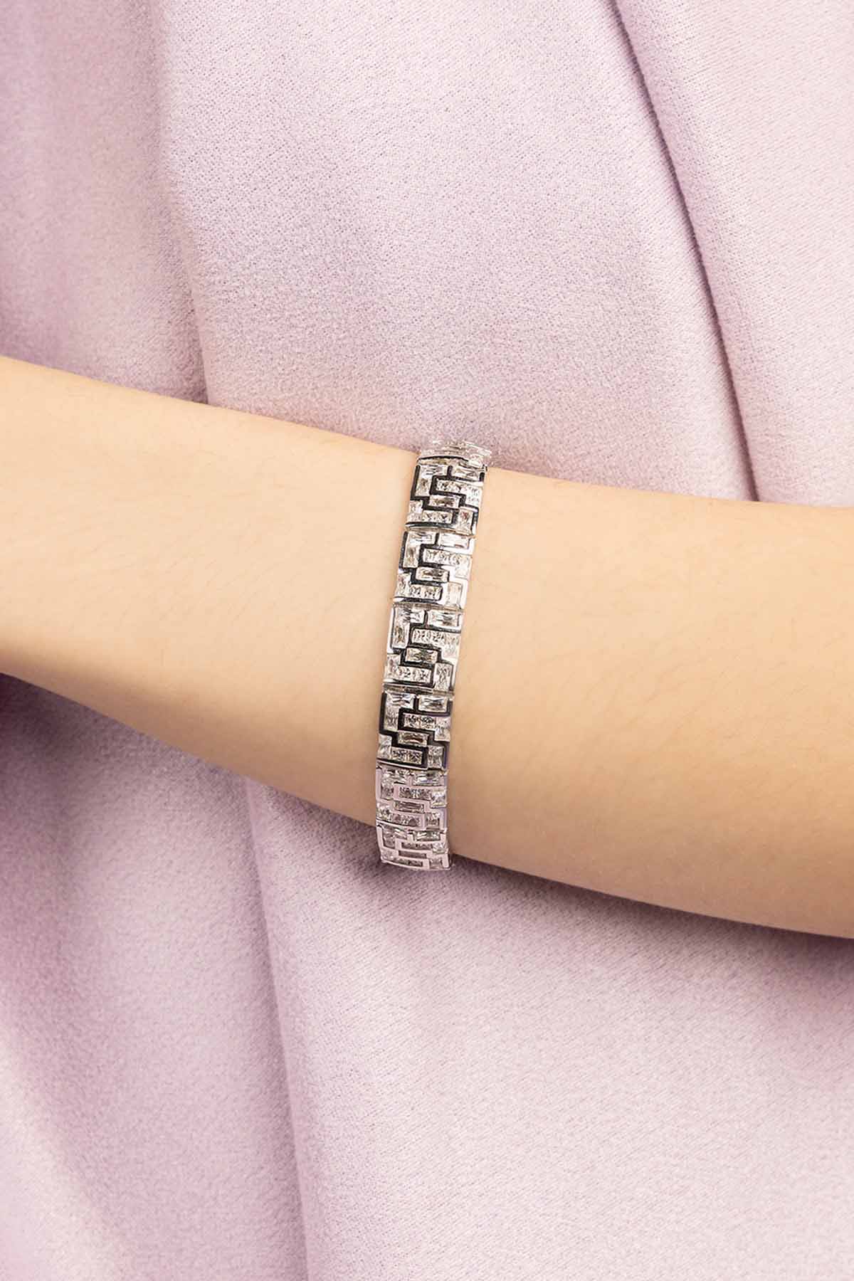 Silver bracelet on a person's wrist with a light pink fabric background