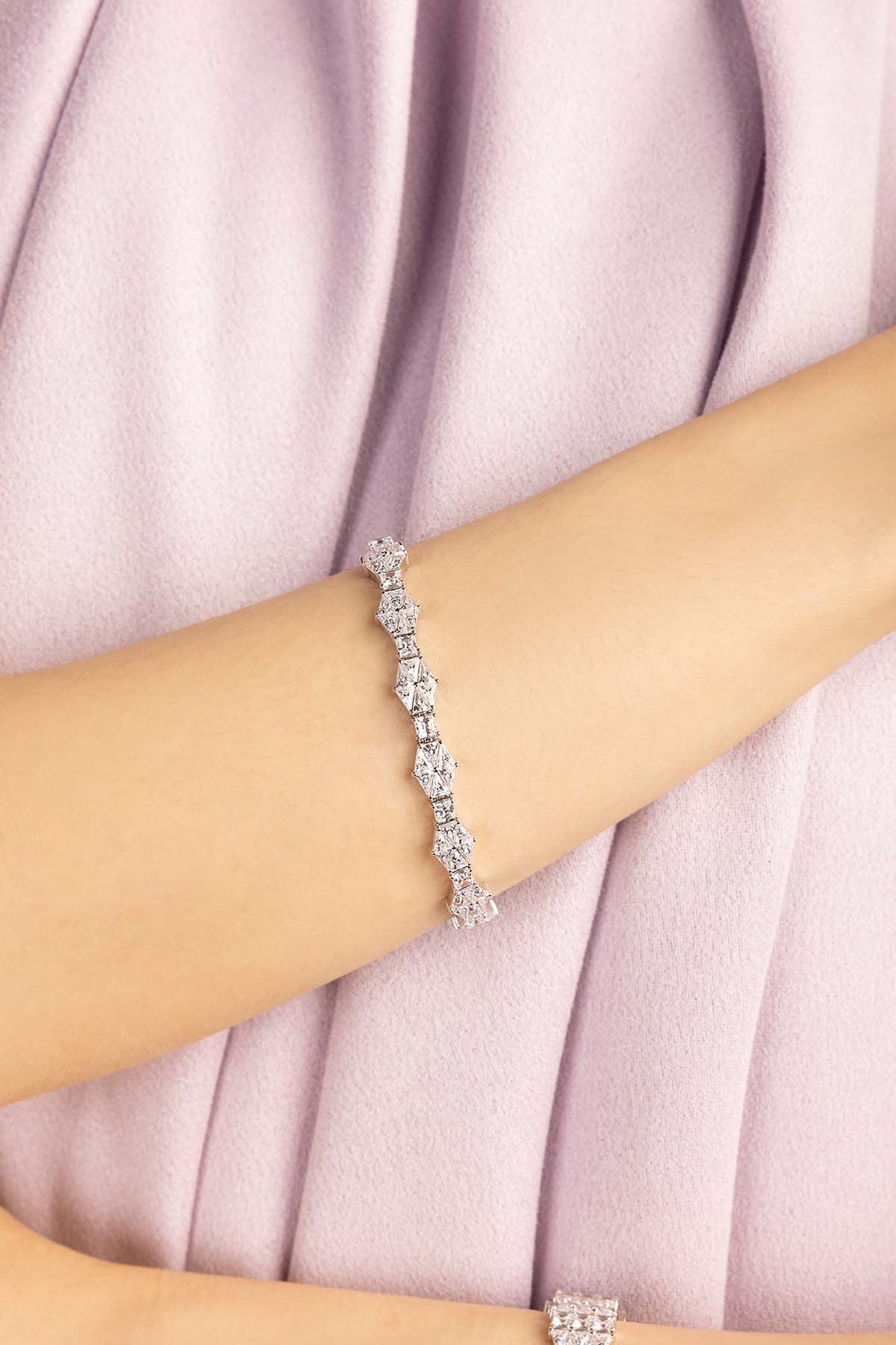Silver bracelet on a person's wrist with a soft pink fabric background