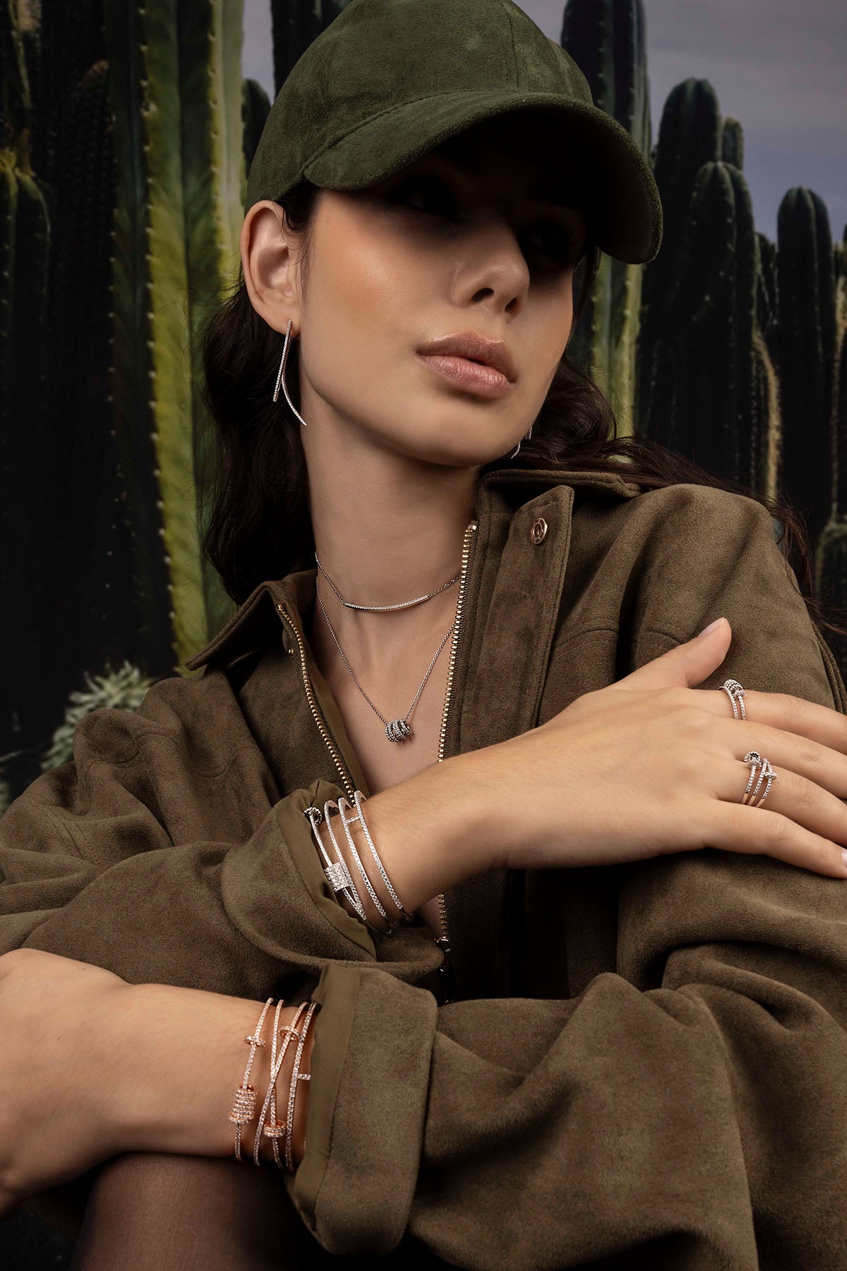 Woman wearing a green cap and brown jacket with cacti in the background