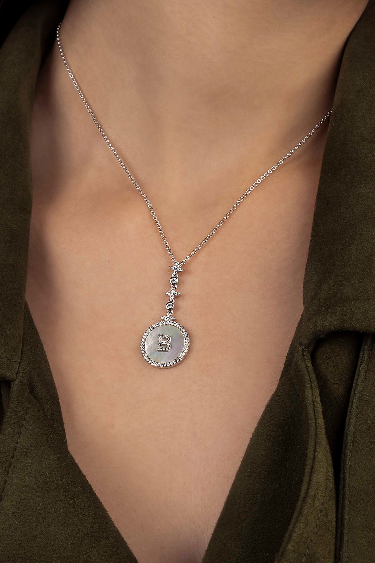 Silver necklace with a pendant on a person wearing a green shirt.