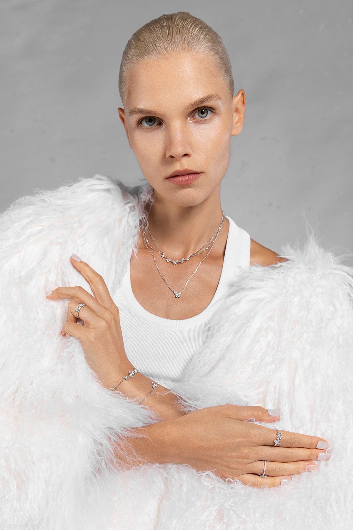 Woman wearing APM MONACO butterfly necklace in silver against a gray background