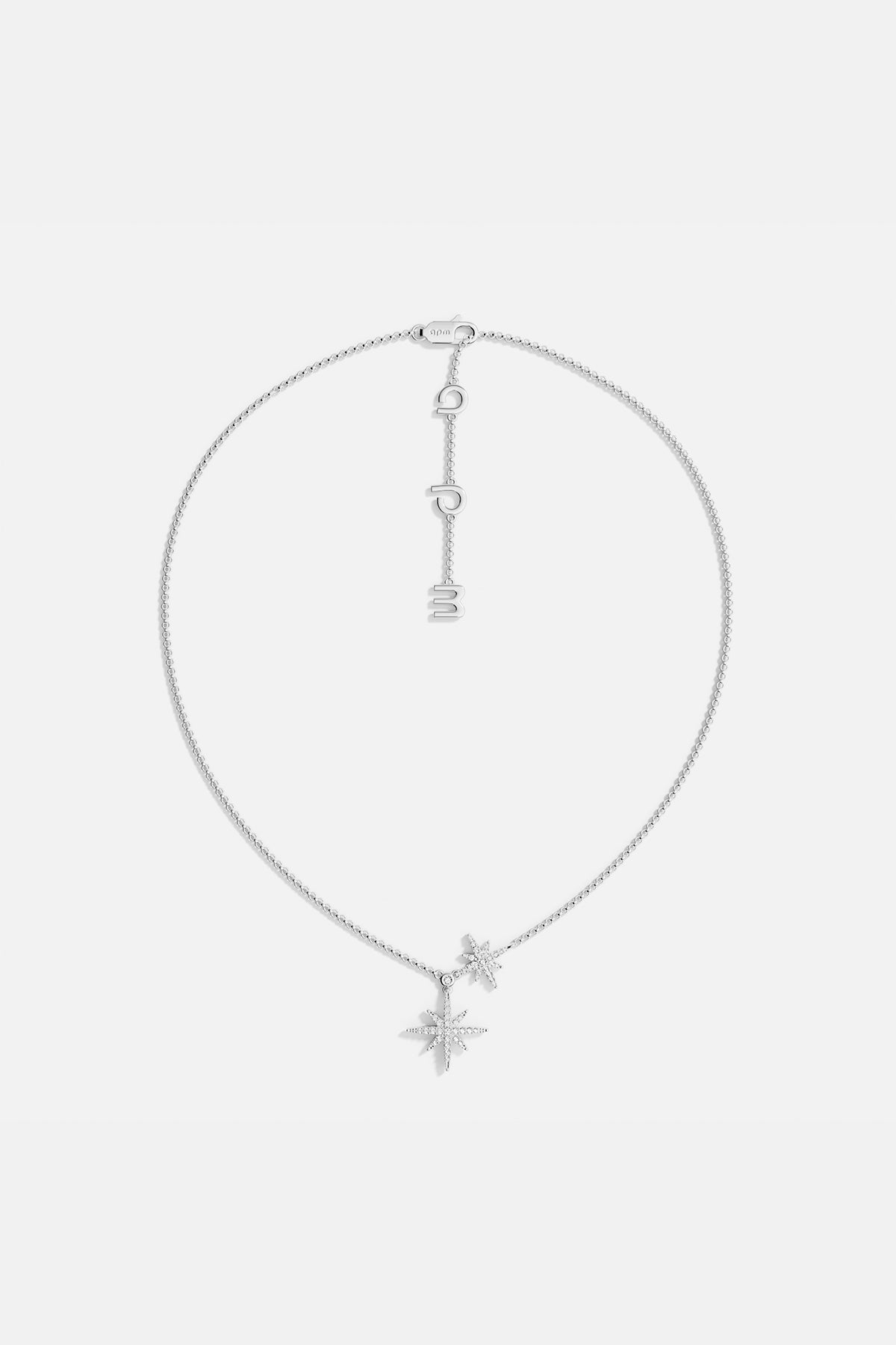 Silver necklace with star-shaped pendants on a light gray background