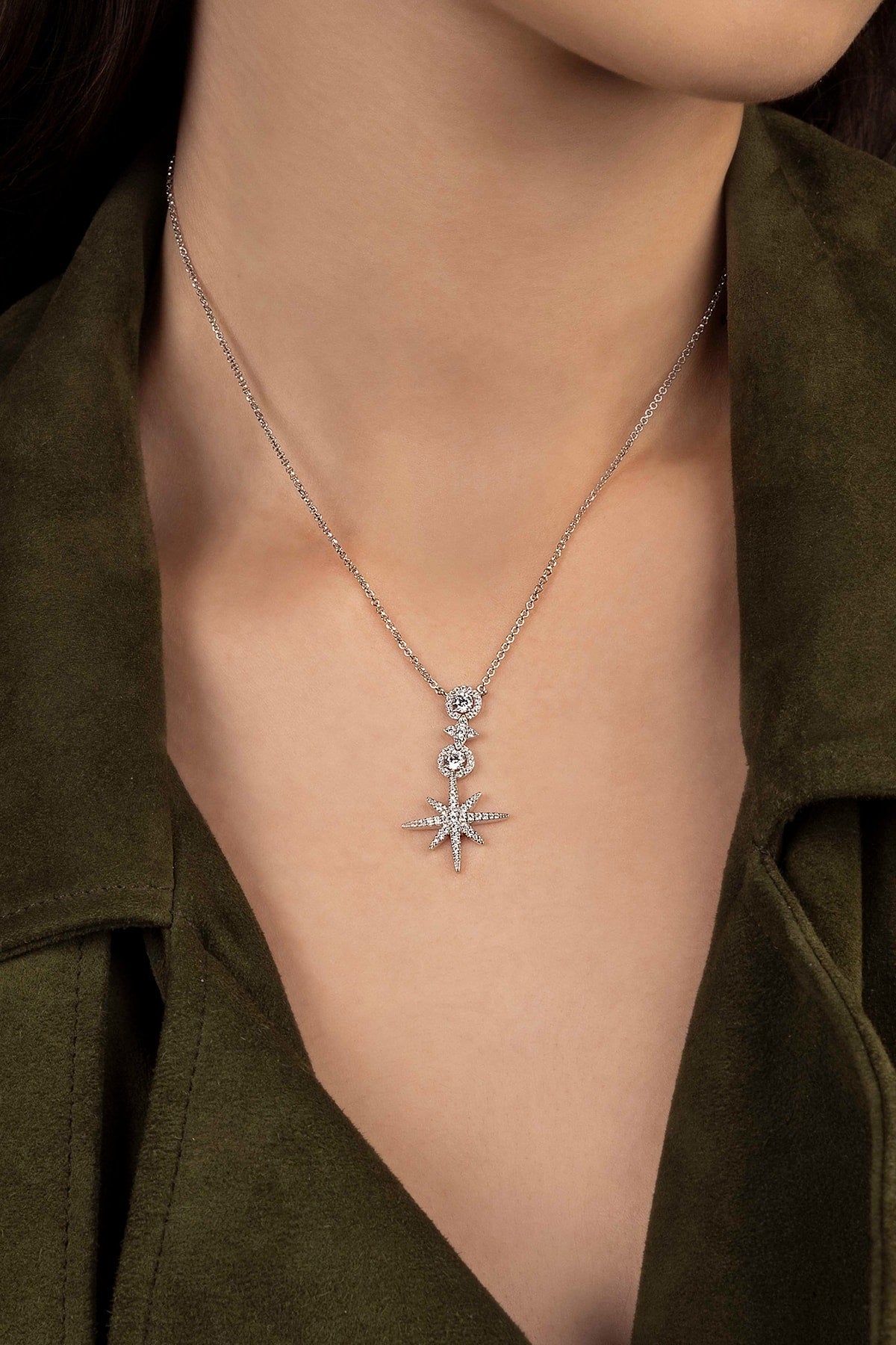 Silver necklace with a star pendant worn by a person in a green outfit.