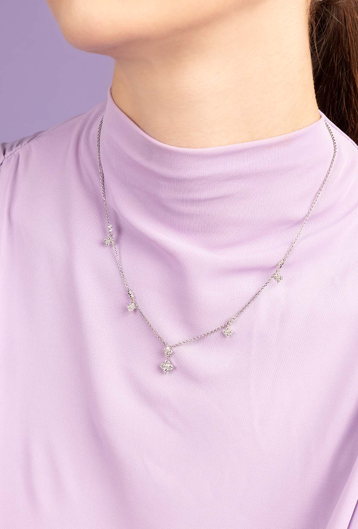 Necklace with small pendants on a person wearing a light purple shirt