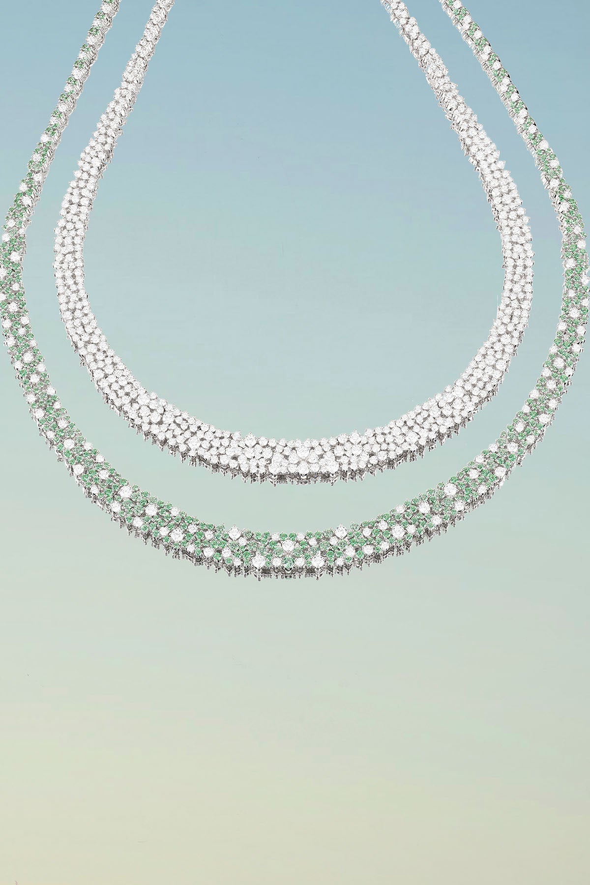Necklaces APM Monaco: two white-diamond and green-emerald choker-style designs.