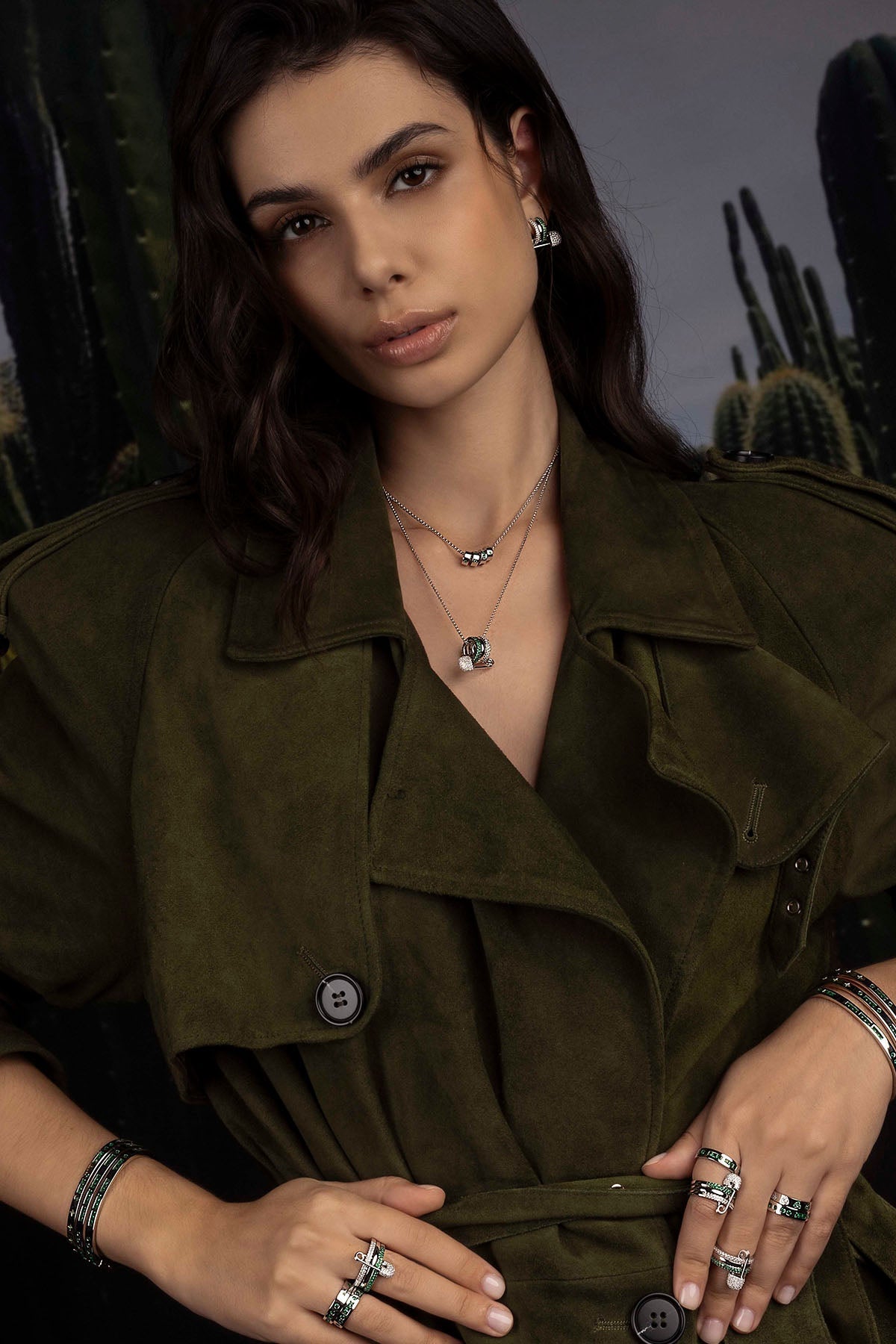 Model wearing a green jacket with jewelry against a cactus background