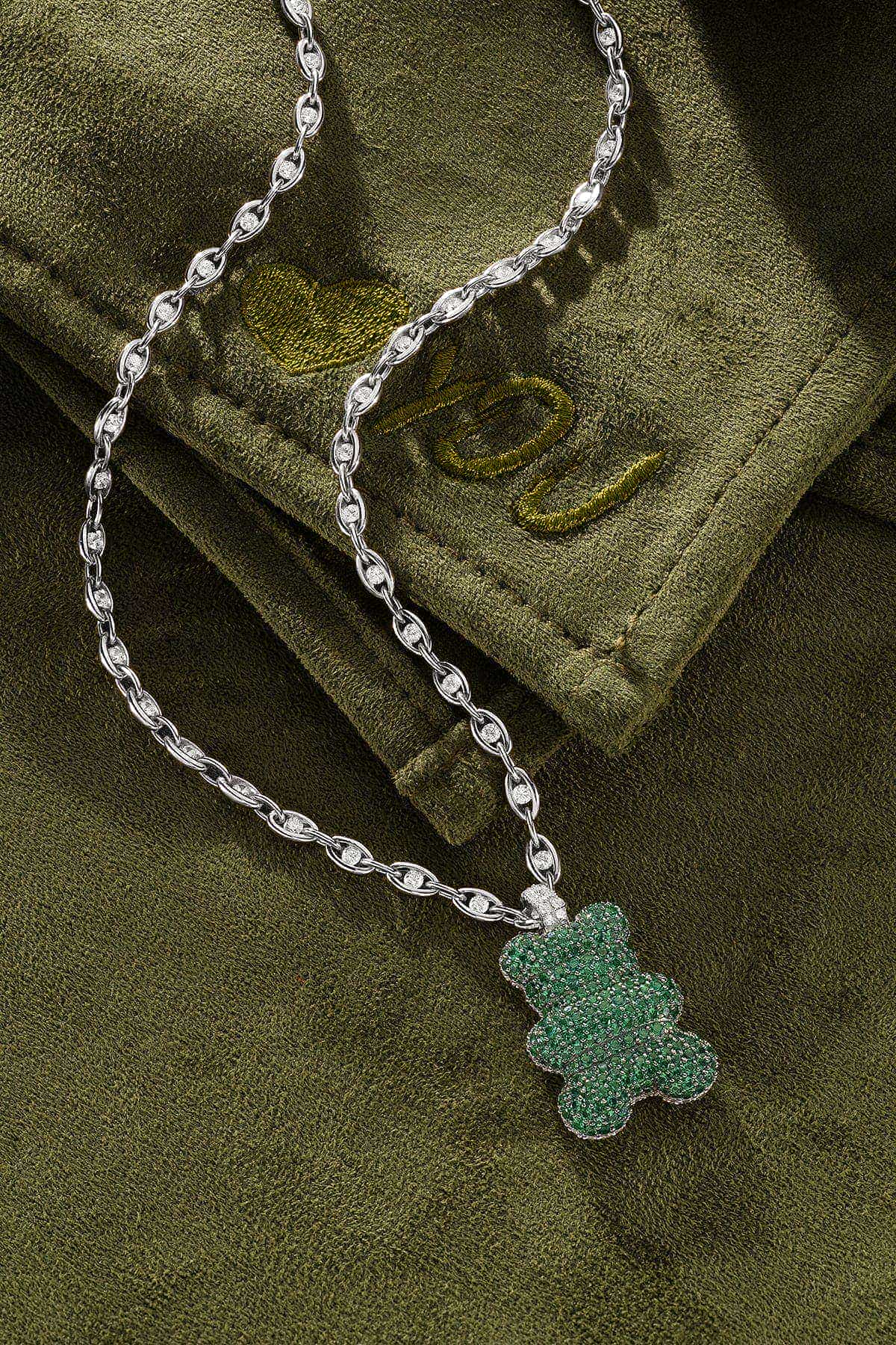 Silver chain with a green pendant on a green fabric background
