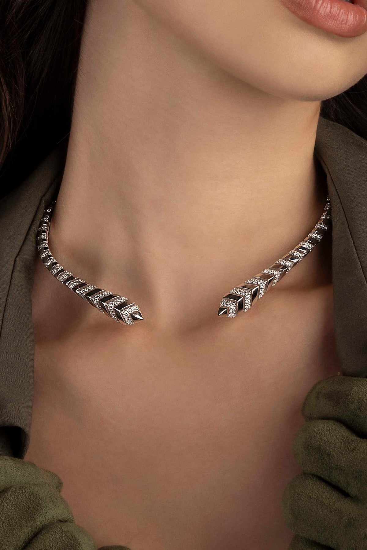 Silver necklace worn by a model, close-up on neck.