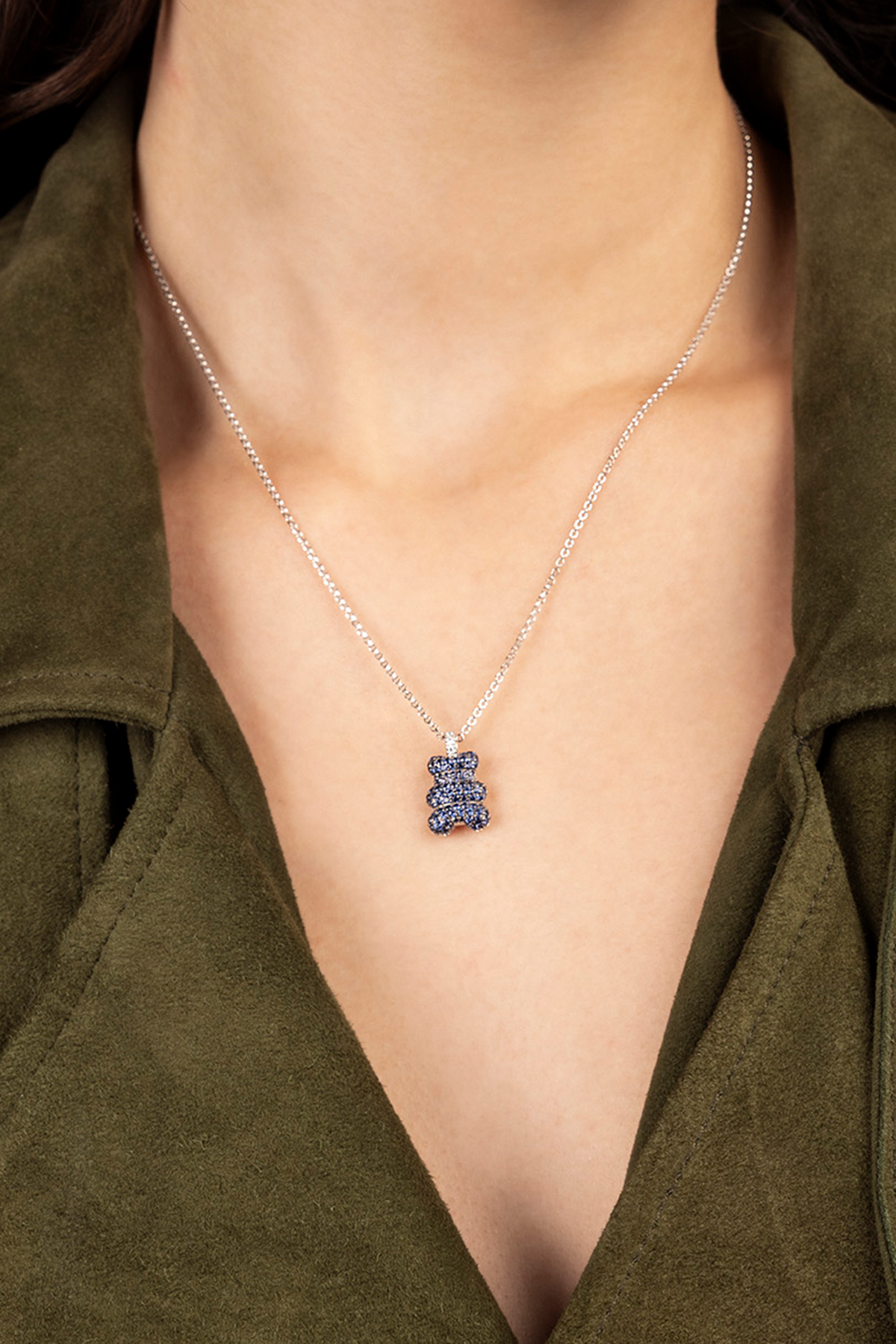 APM MONACO Necklace with a blue YUMMY BEAR pendant worn by a person in an olive green outfit.