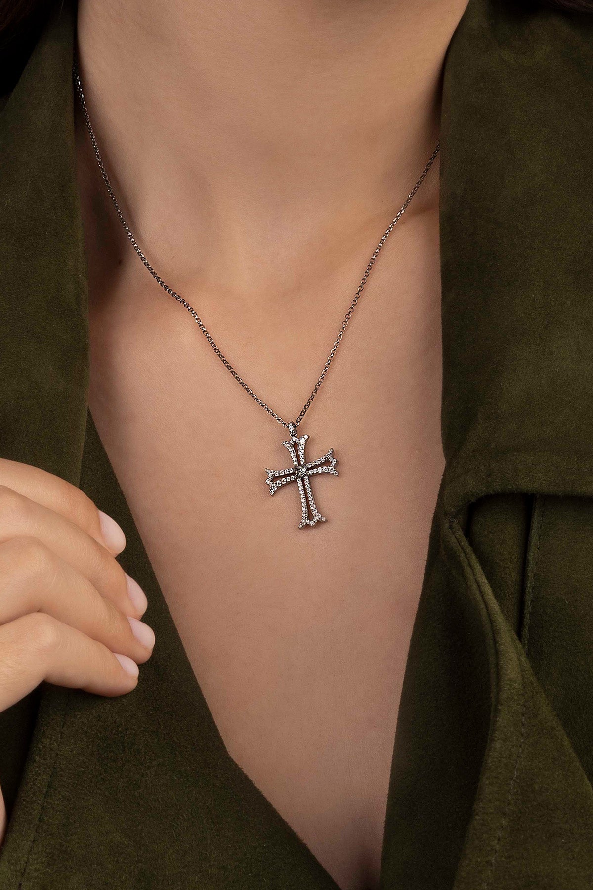 Silver cross necklace on a model wearing a green outfit