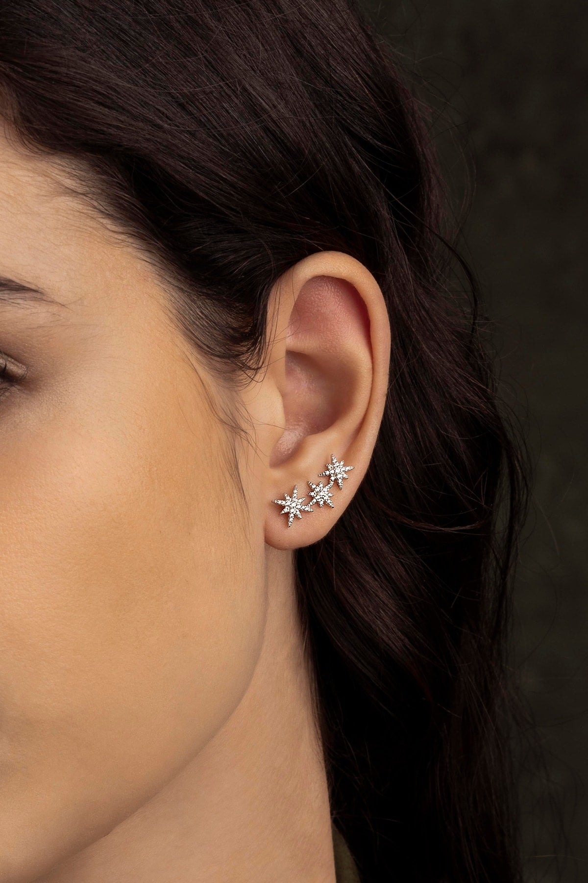 Close-up of a person wearing star-shaped earrings with a dark background
