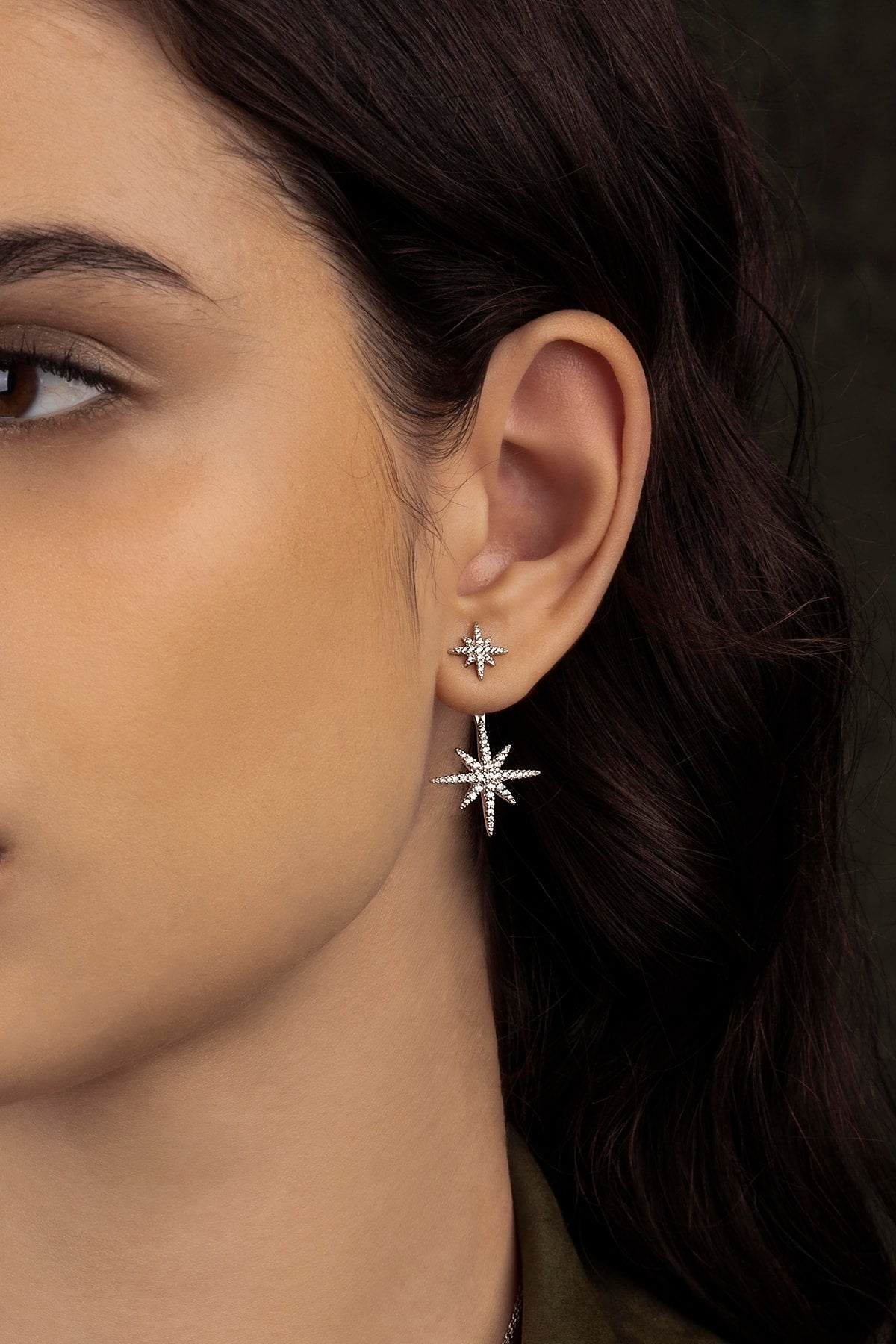 Close-up of a woman wearing star-shaped earrings with a dark background