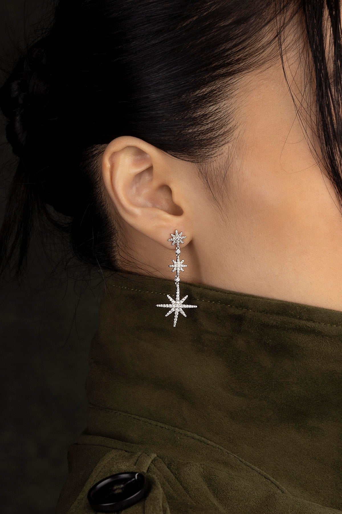 Close-up of an ear wearing a star-shaped earring with a dark background