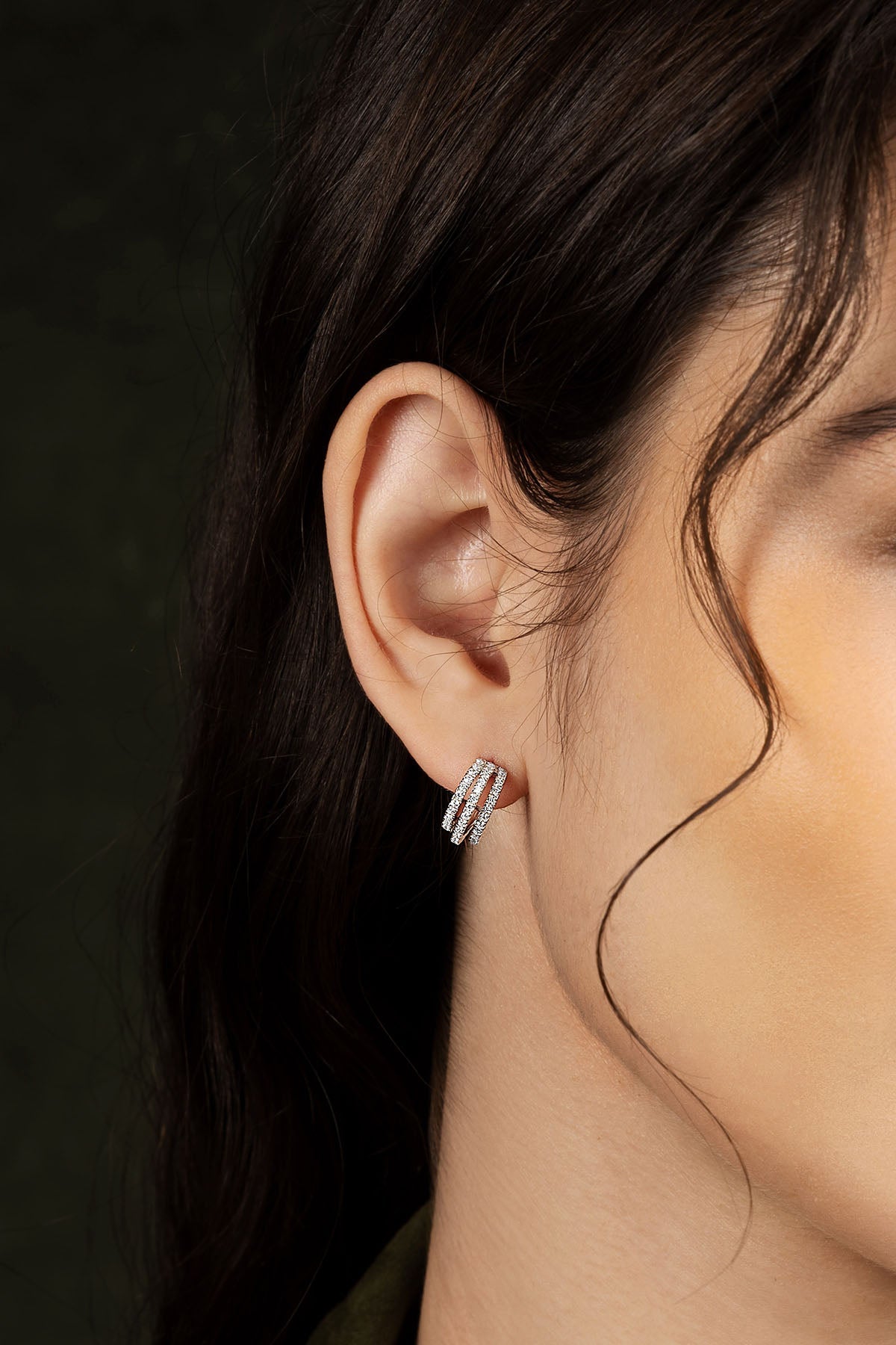 Close-up of an ear wearing a earring with a dark background