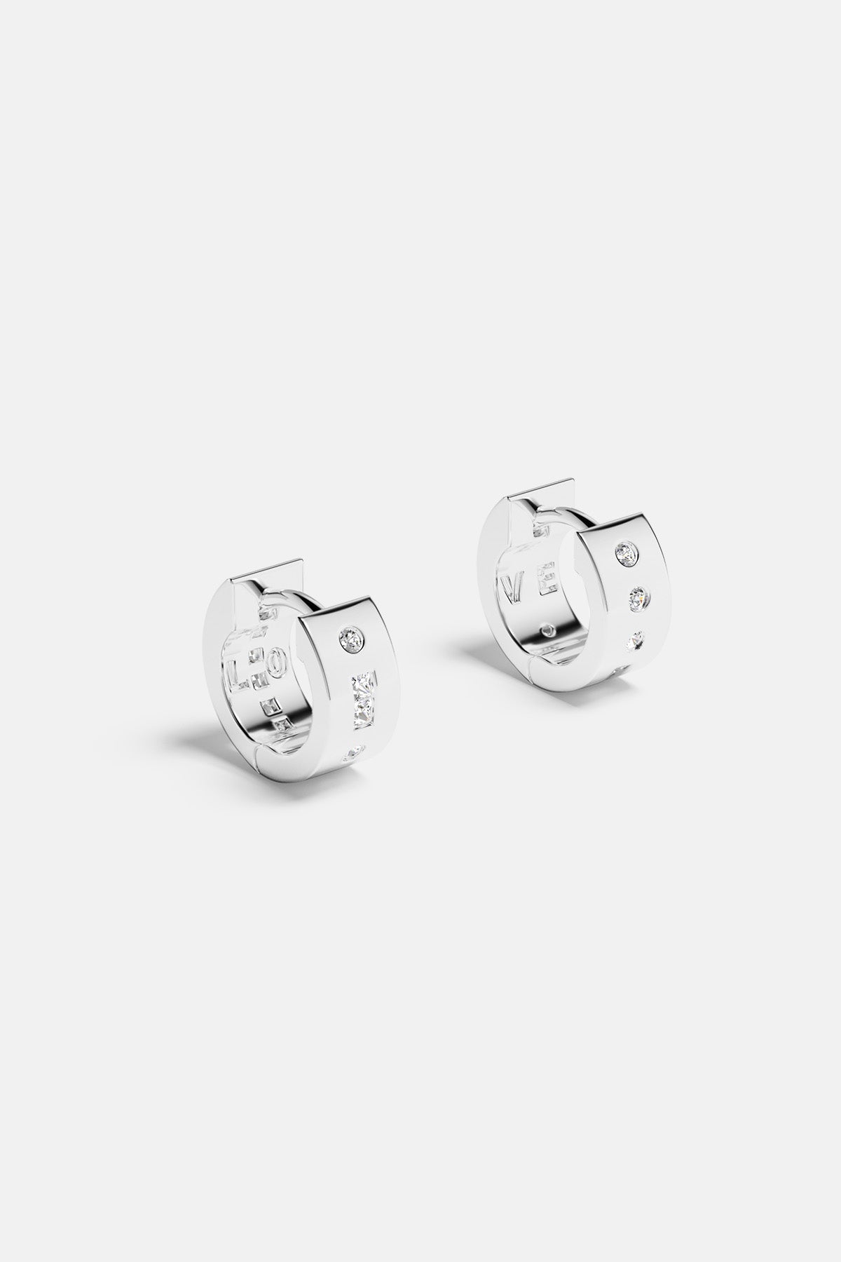 Earrings APM Monaco white-silver-toned huggie earrings with three inset diamonds each.