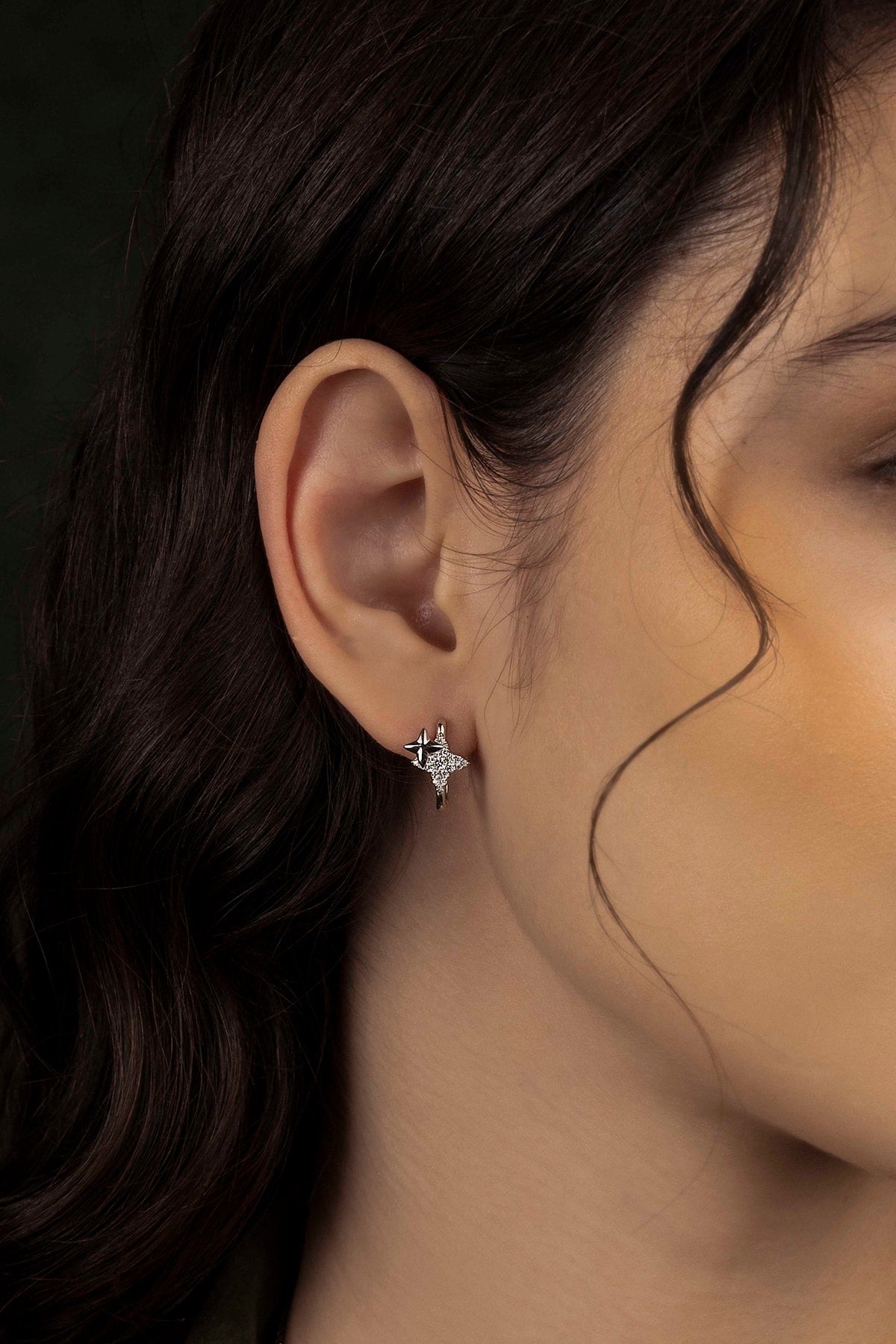 Close-up of a woman wearing earring with a dark background