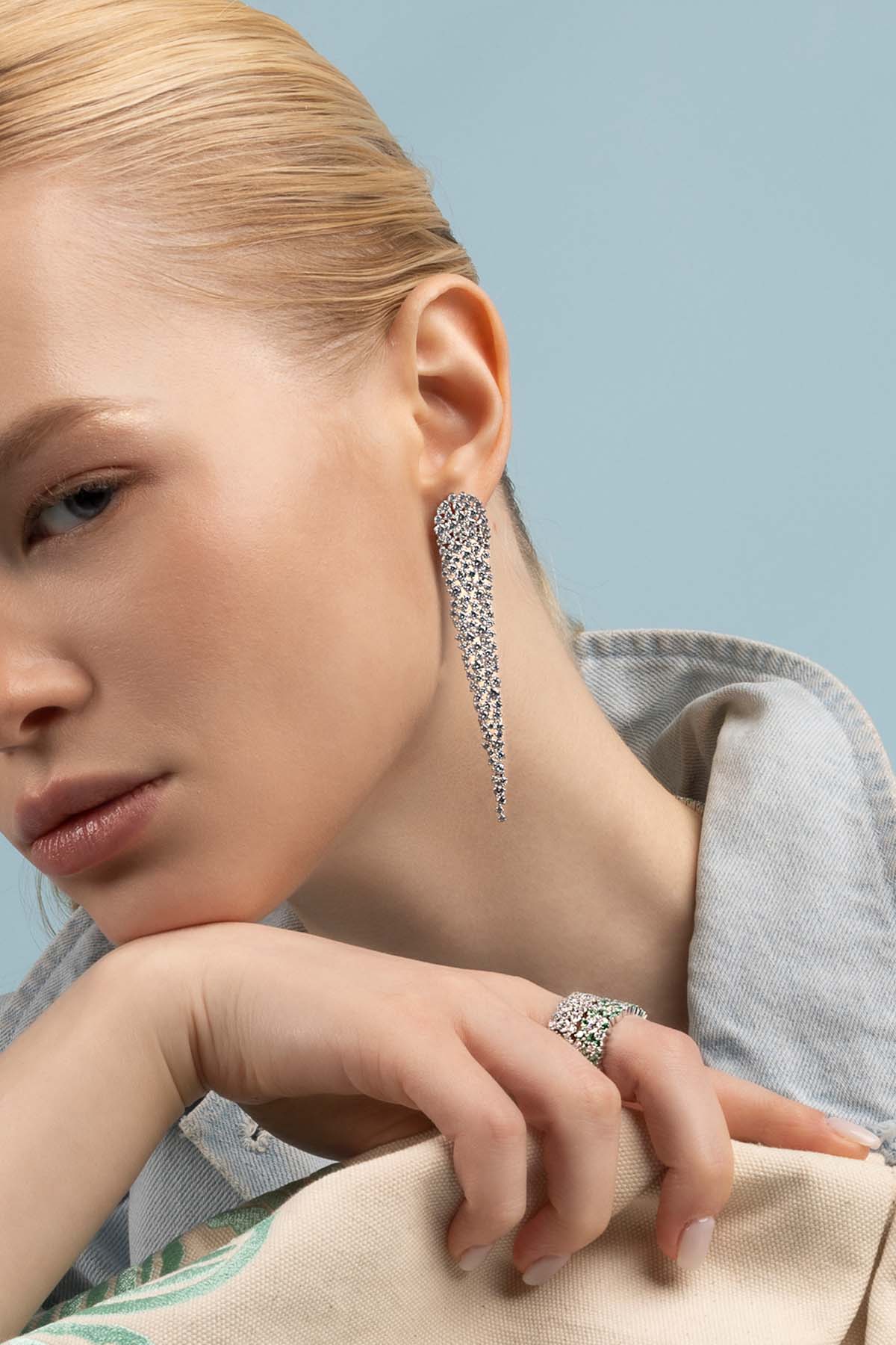 Earrings — APM Monaco: long pavé diamond drop earrings; Ring — APM Monaco: large diamond with emerald centerpiece.