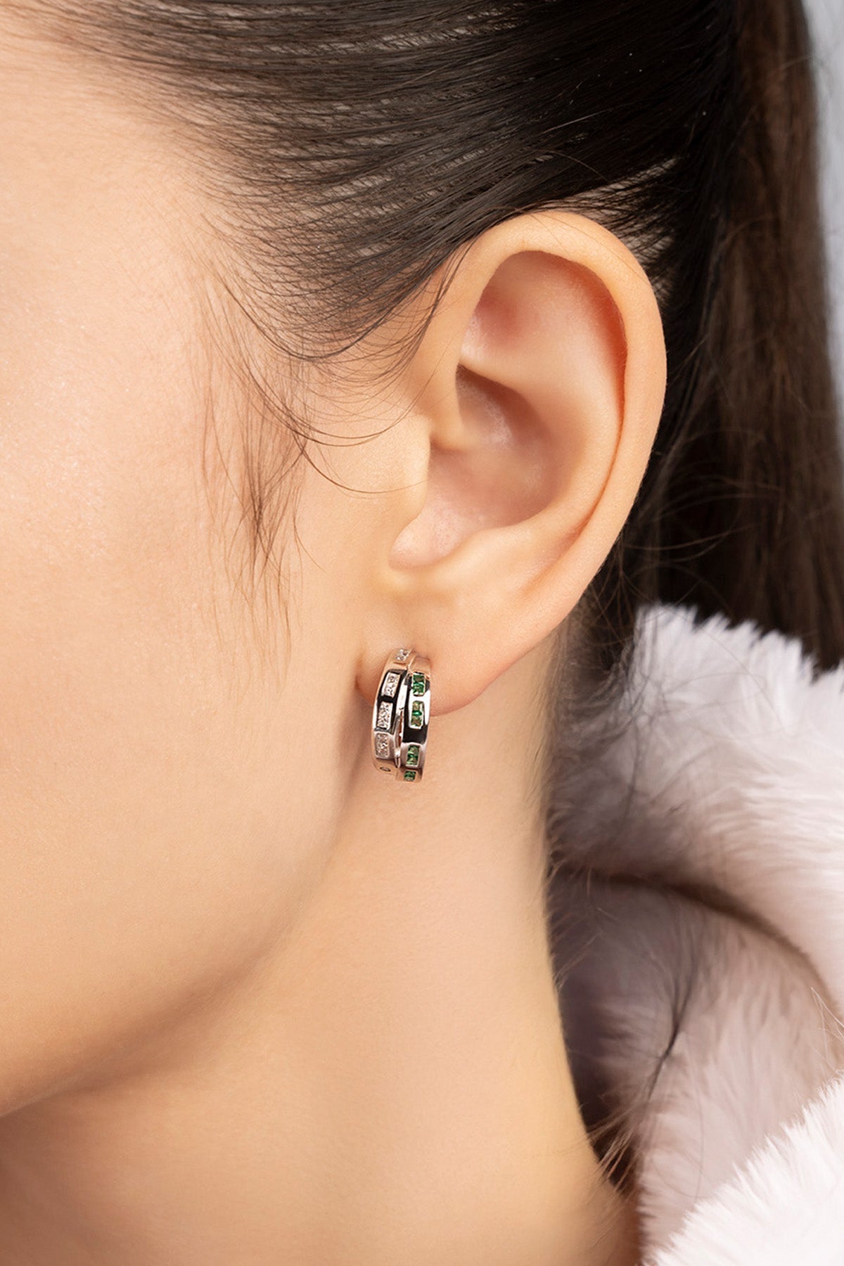 Close-up of an ear wearing a silver hoop earring.