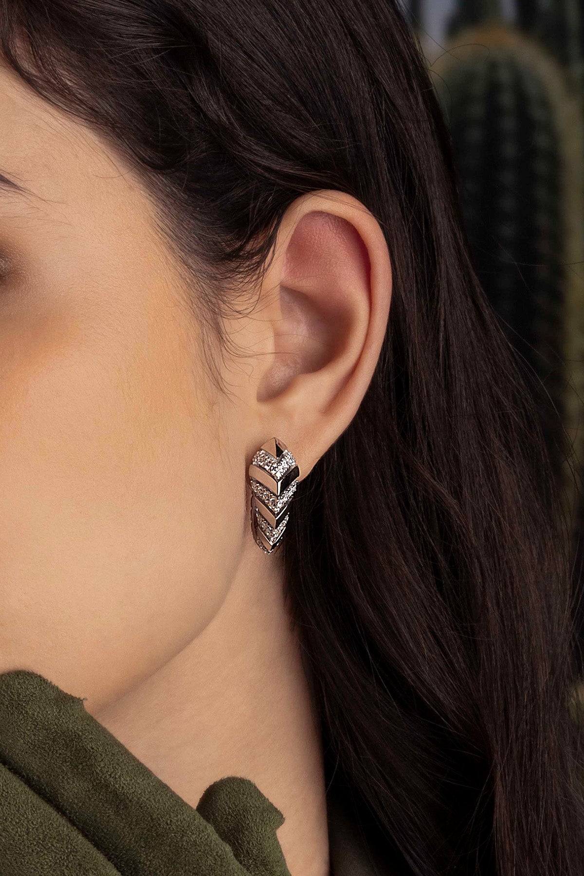 Close-up of a model wearing a kaa earring with a cactus in the background