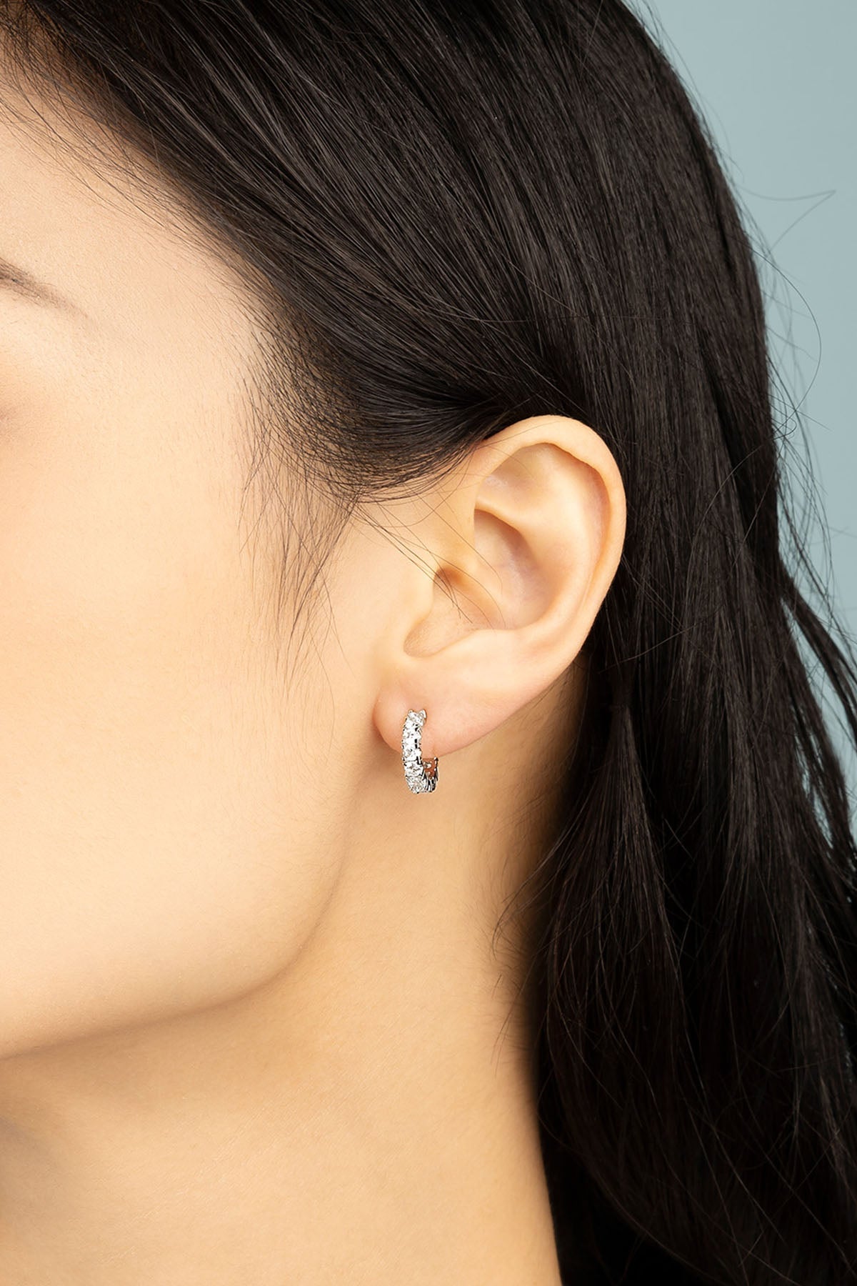 Earrings APM Monaco pavé huggie hoops with small crystal stones in white tone.