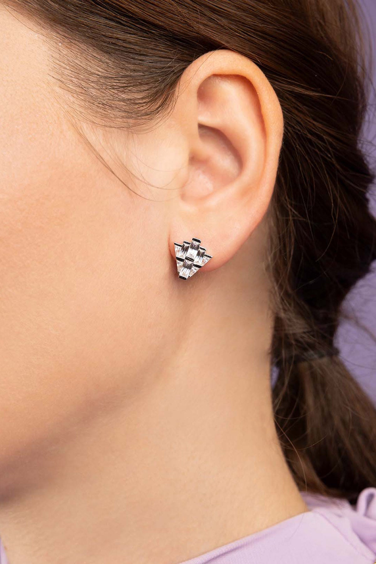 Close-up of a person wearing a silver earring with a geometric design.
