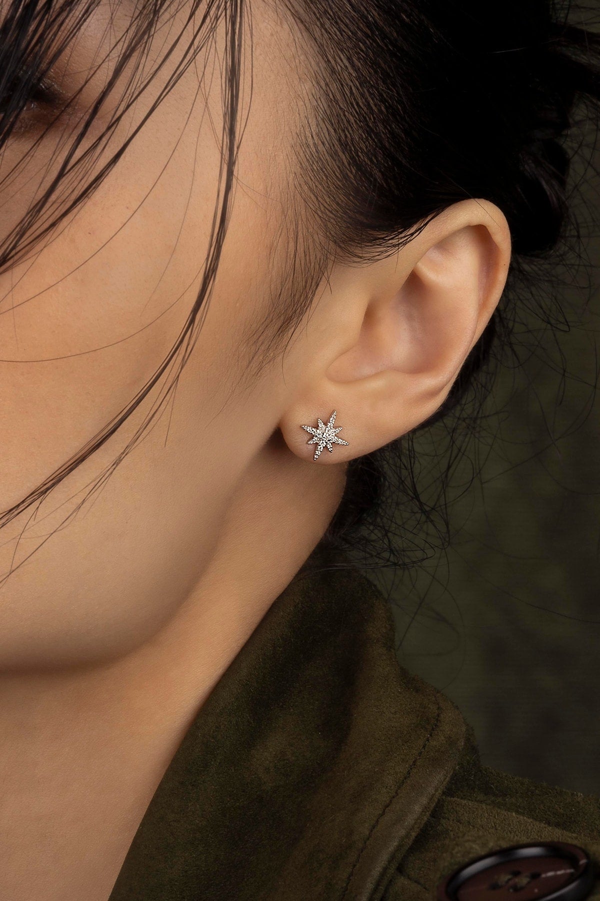 Close-up of a person wearing a star-shaped earring with a dark background