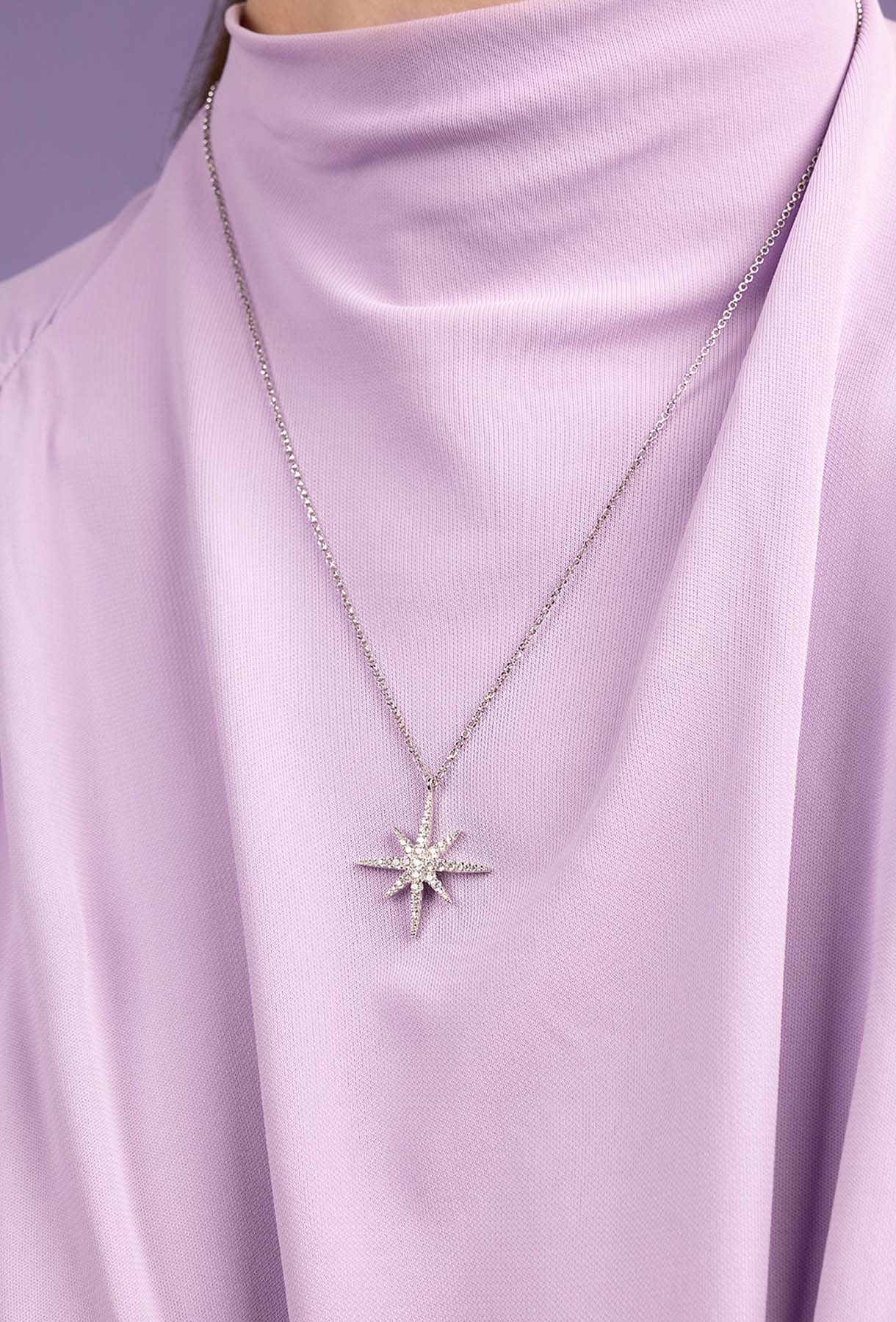 Star-shaped pendant necklace on a person wearing a light purple turtleneck.