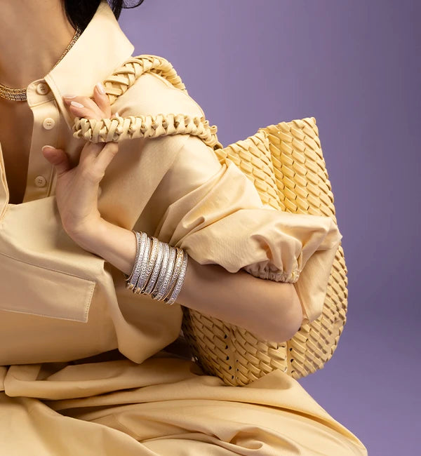 Person holding yellow APM MONACO handbag with a plain purple background