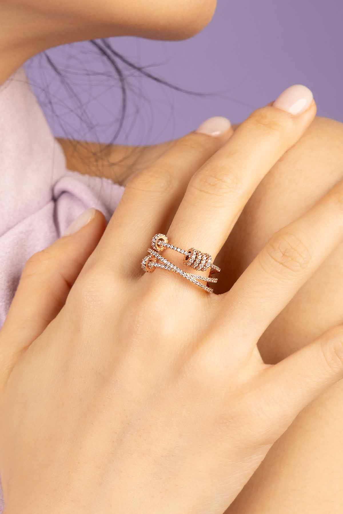 Close-up of a hand wearing APM MONACO rose gold triple ring with sliding hoops